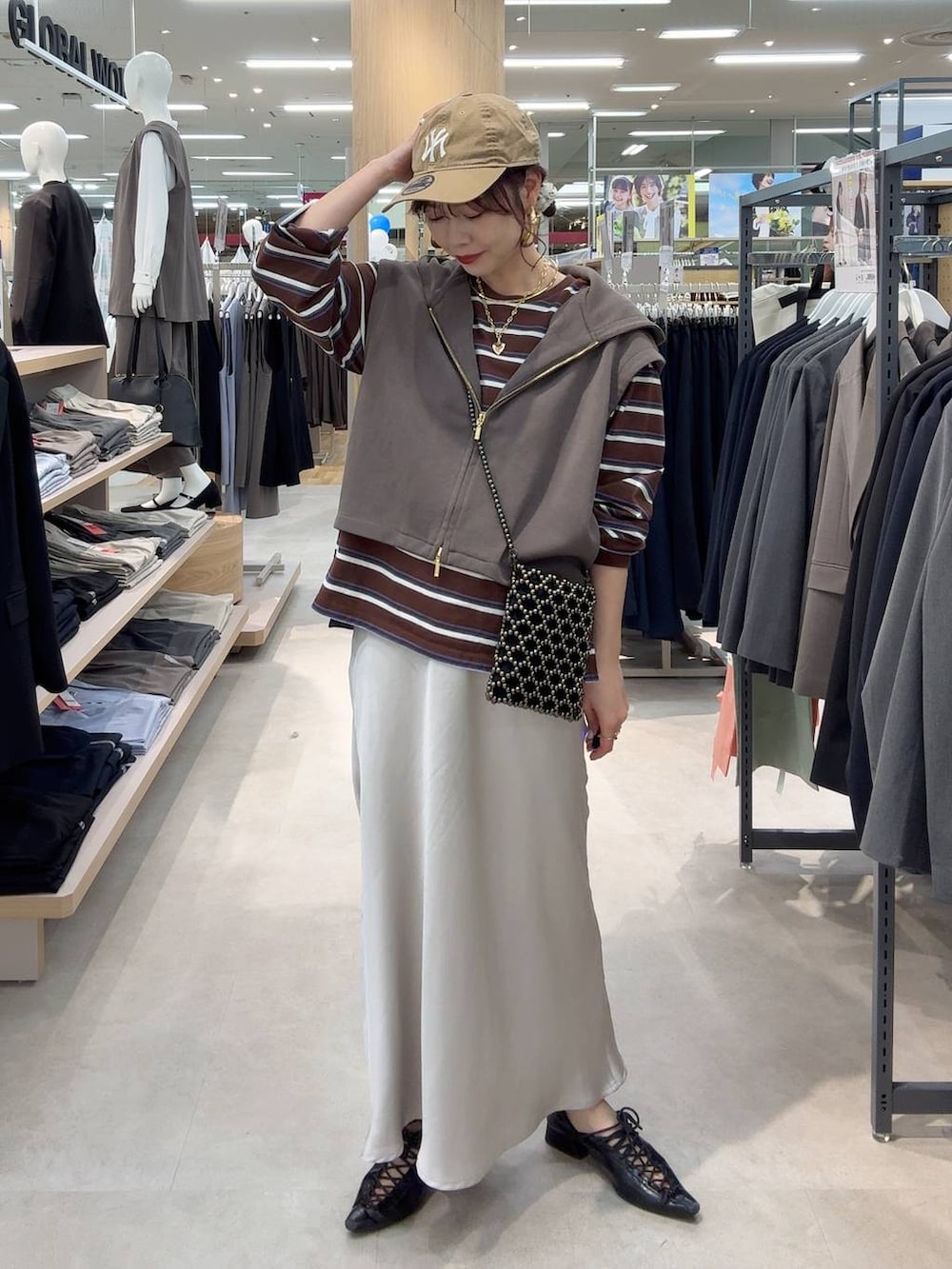 ブラック系のショルダーバッグ、グレー系のスカート、ブラウン系のTシャツ/カットソーを着用したレディースの春コーディネートの2枚目の写真