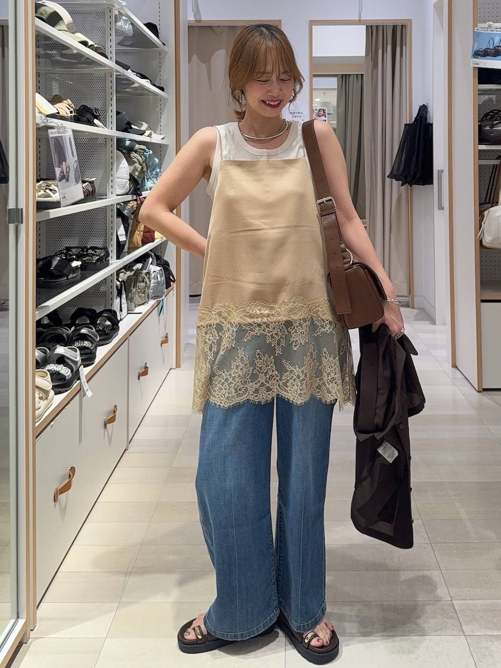 ブルー系のデニムパンツ、ホワイト系のタンクトップ、ブラウン系のシャツ/ブラウスを着用したレディースの春コーディネートの2枚目の写真