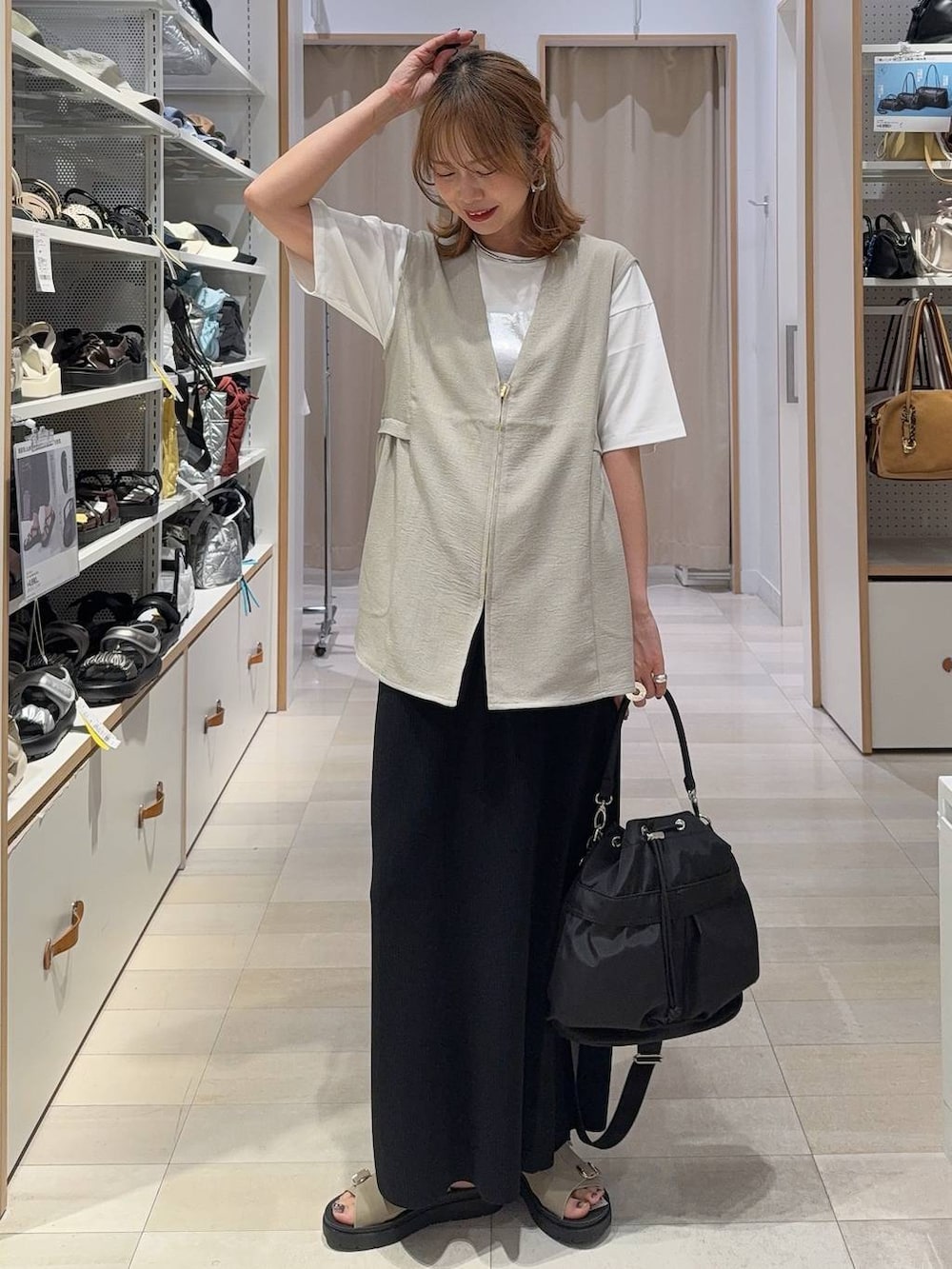ブラック系のショルダーバッグ、ベージュ系のベスト、ホワイト系のTシャツ/カットソーを着用したレディースの夏コーディネートの2枚目の写真