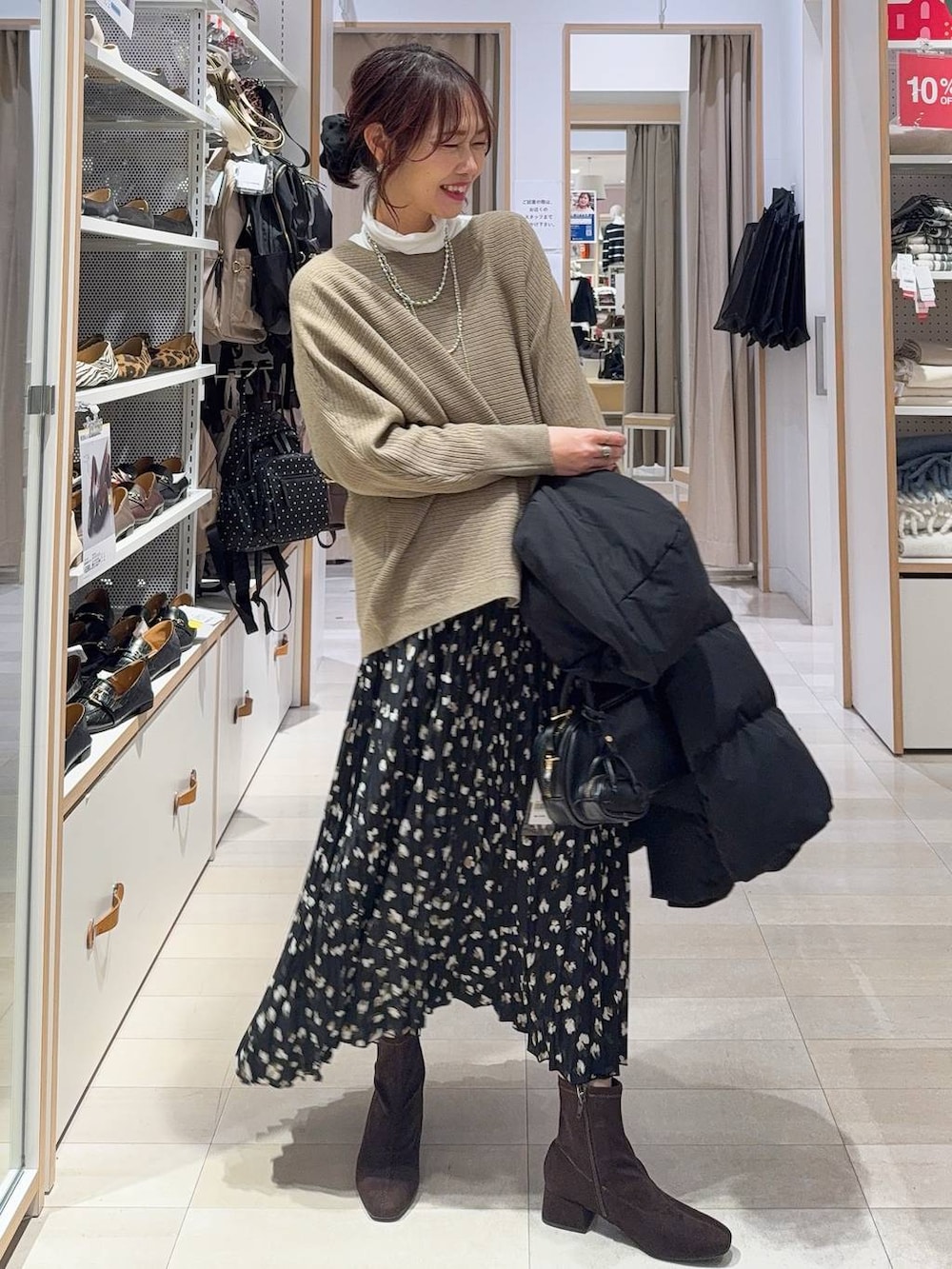 ベージュ系のダウンジャケット/コート、ブラック系のショルダーバッグ、ブラウン系のニット/セーターを着用したレディースの冬コーディネートの3枚目の写真