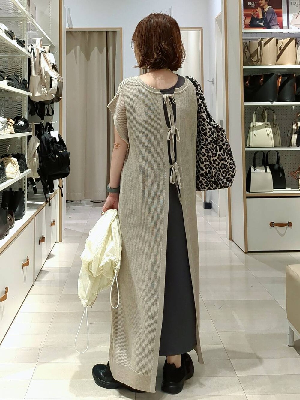 ブラック系のスニーカー、ブルー系のデニムパンツ、ベージュ系のワンピースを着用したレディースの春コーディネートの8枚目の写真