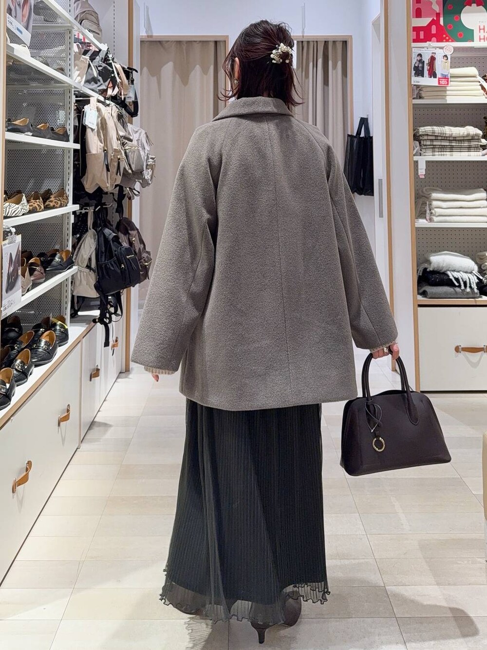 ブラウン系のショルダーバッグ、ブラウン系のチェスターコート、グレー系のワンピースを着用したレディースの冬コーディネートの6枚目の写真