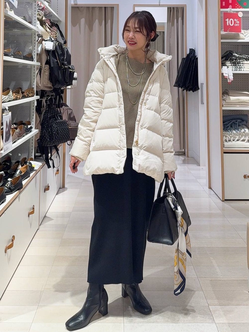 ベージュ系のダウンジャケット/コート、ブラック系のショルダーバッグ、ブラウン系のニット/セーターを着用したレディースの冬コーディネートの2枚目の写真