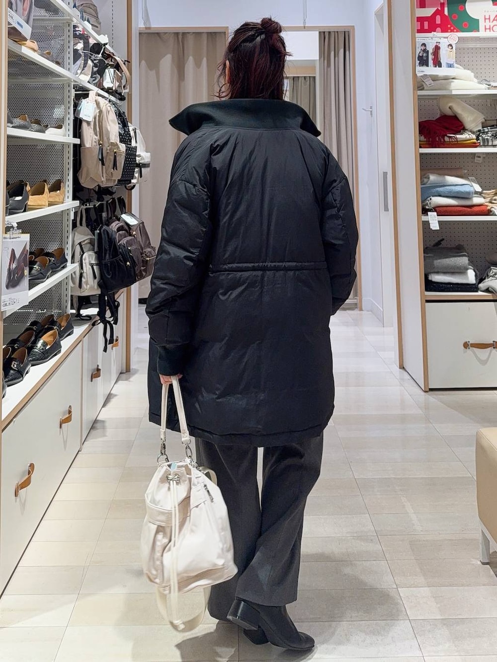 ホワイト系のショルダーバッグ、ブラック系のダウンジャケット/コート、ホワイト系のニット/セーターを着用したレディースの冬コーディネートの5枚目の写真