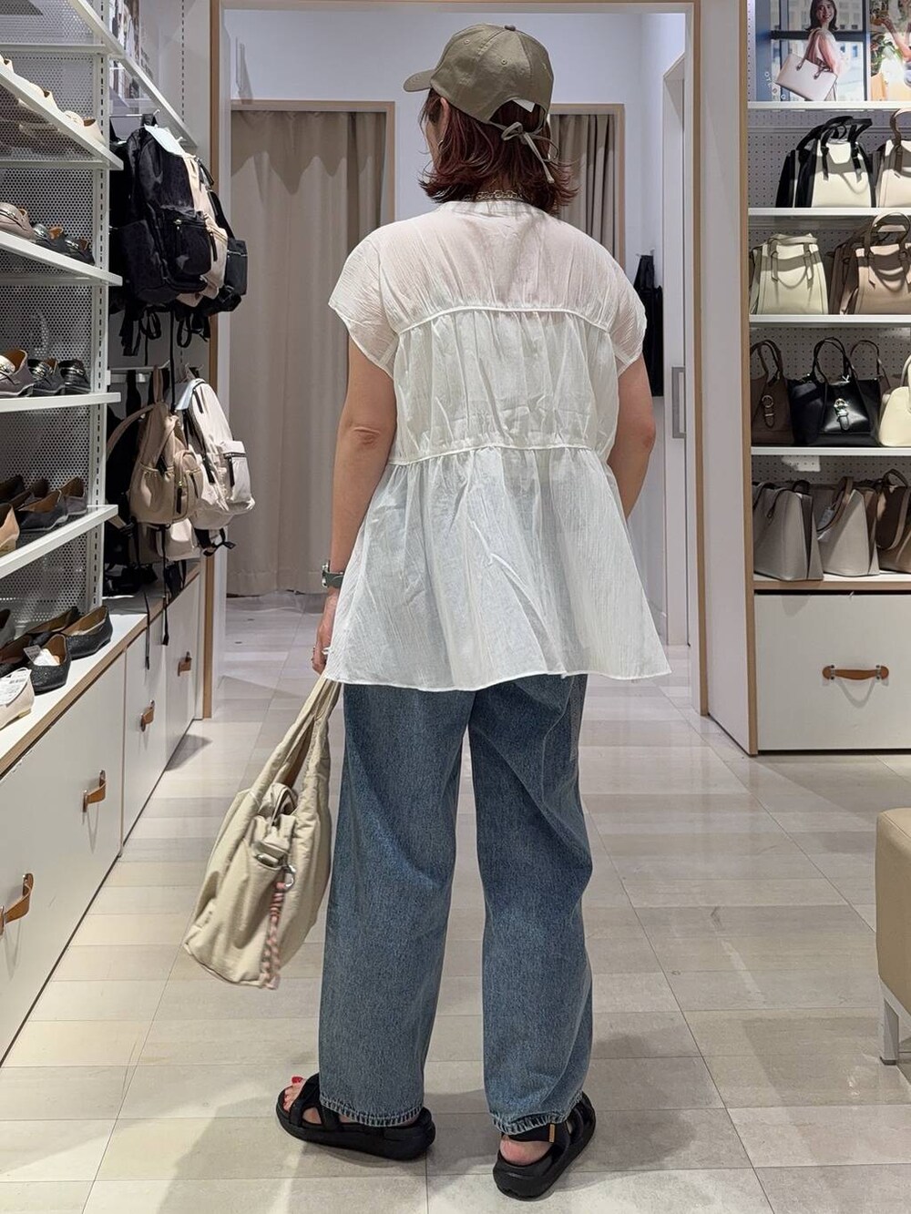 ブルー系のデニムパンツ、ベージュ系のキャミソール、ベージュ系のトートバッグを着用したレディースの夏コーディネートの7枚目の写真