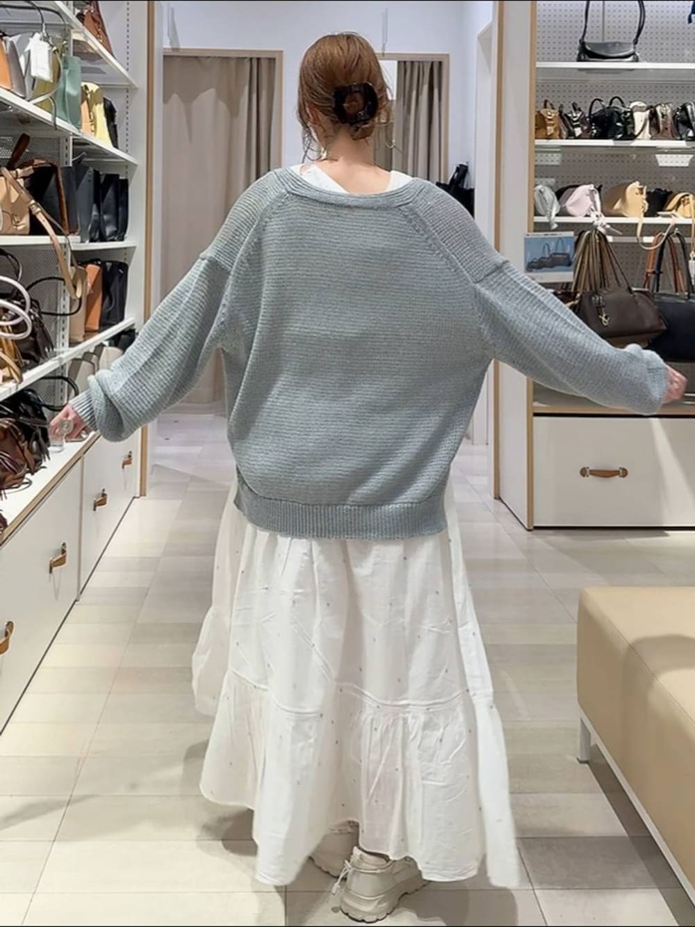 シルバー系のボストンバッグ、ホワイト系のスカート、ホワイト系のタンクトップを着用したレディースの春コーディネートの3枚目の写真