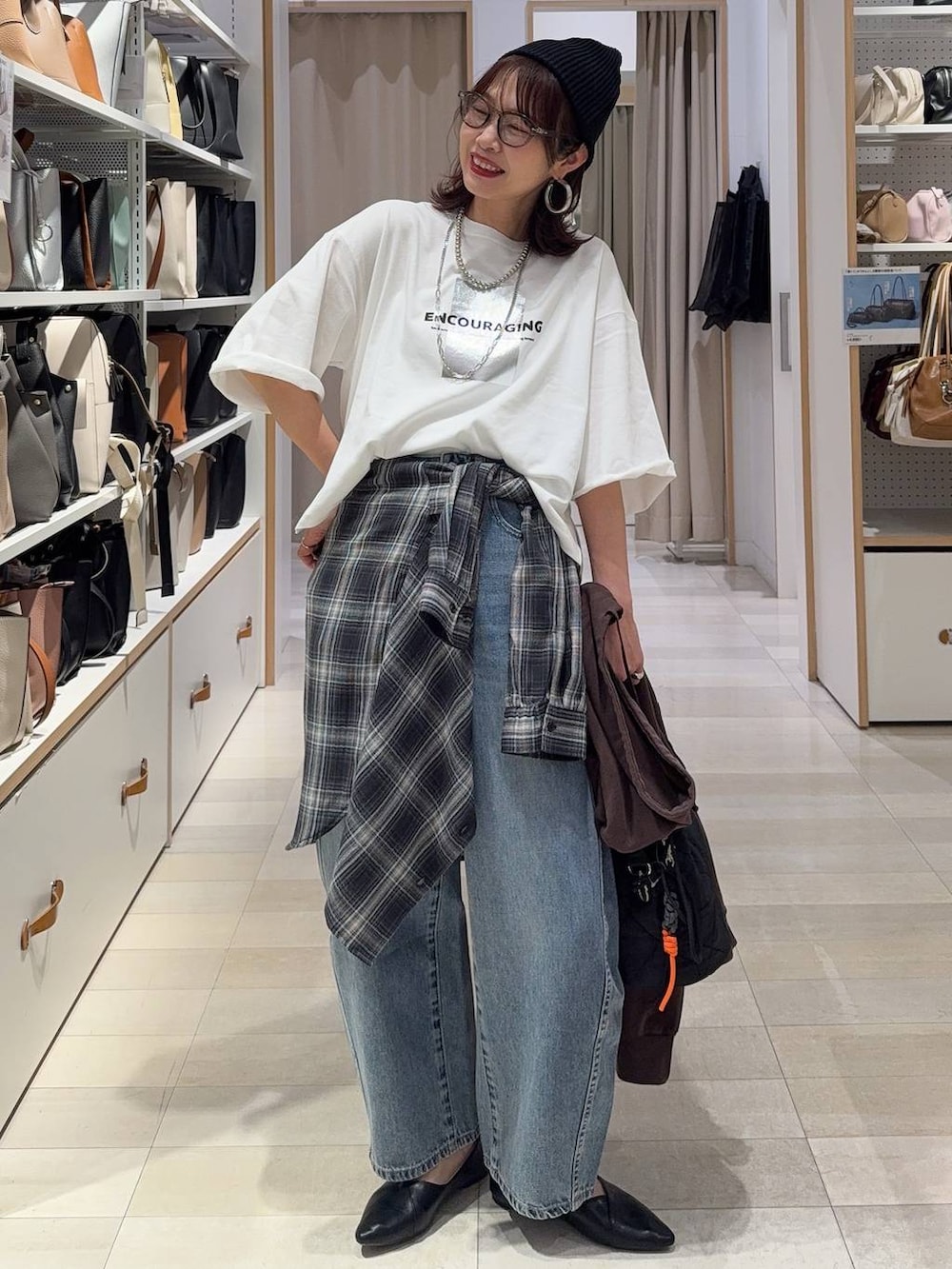 ブラック系のパンプス、ブラック系のハンドバッグ、ブルー系のデニムパンツを着用したレディースの春コーディネートの2枚目の写真