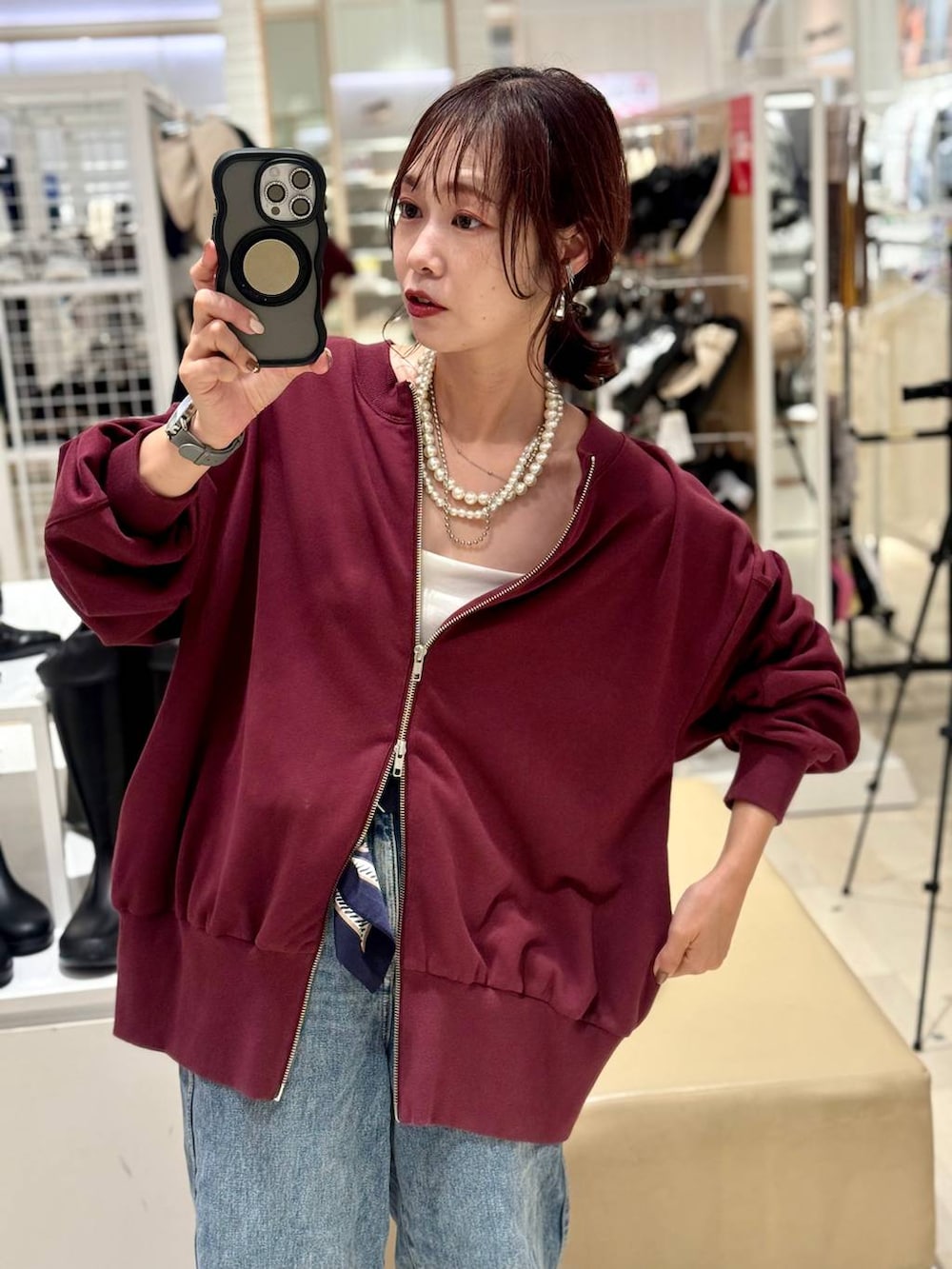 ホワイト系のキャミソール、ブルー系のデニムパンツ、ブラック系のボストンバッグを着用したレディースの秋コーディネートの2枚目の写真