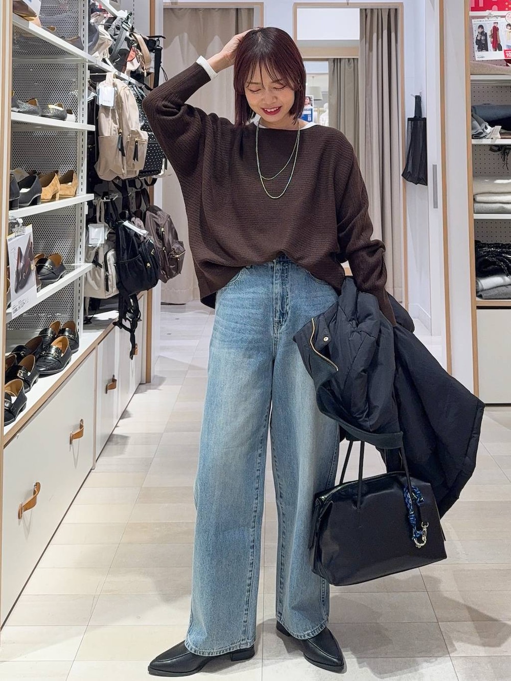 ブラック系のダウンジャケット/コート、ブラック系のボストンバッグ、ブルー系のデニムパンツを着用したレディースの冬コーディネートの2枚目の写真