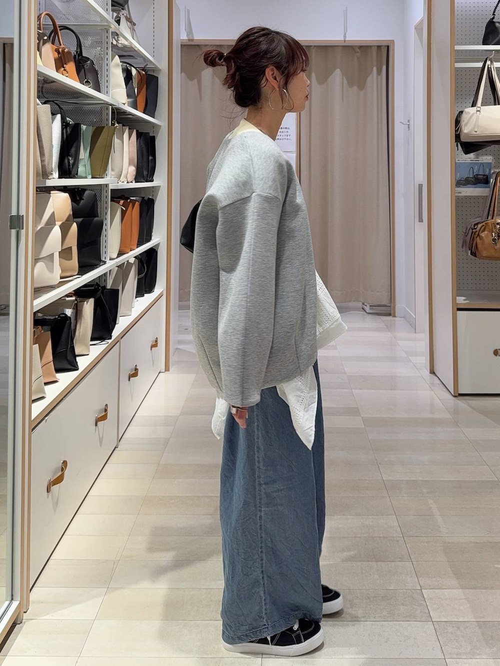 グレー系のブルゾン、イエロー系のカーディガン/ボレロ、ブラック系のスニーカーを着用したレディースの春コーディネートの4枚目の写真