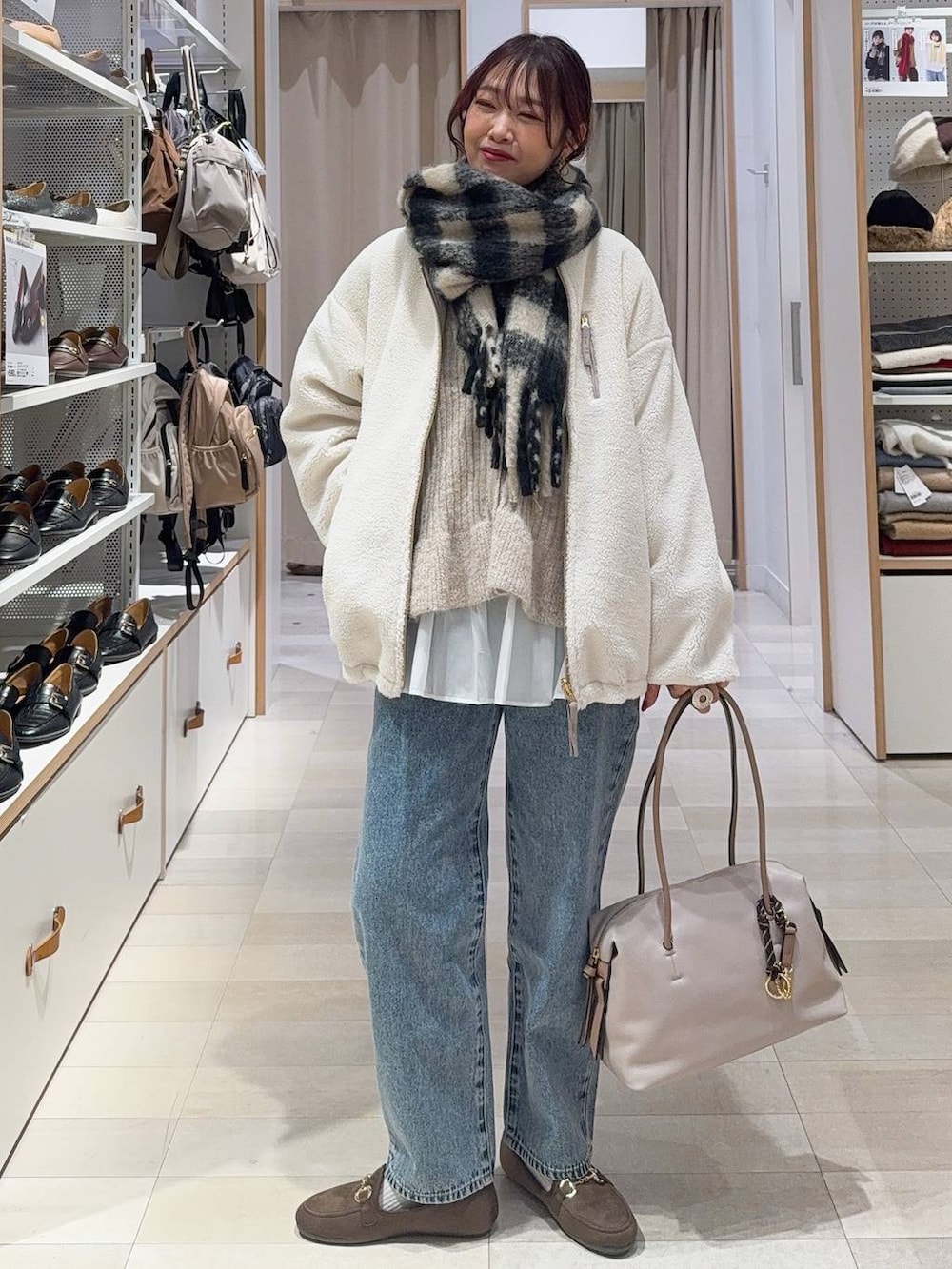 ホワイト系のボストンバッグ、ホワイト系のブルゾン、ブルー系のデニムパンツを着用したレディースの秋コーディネートの4枚目の写真