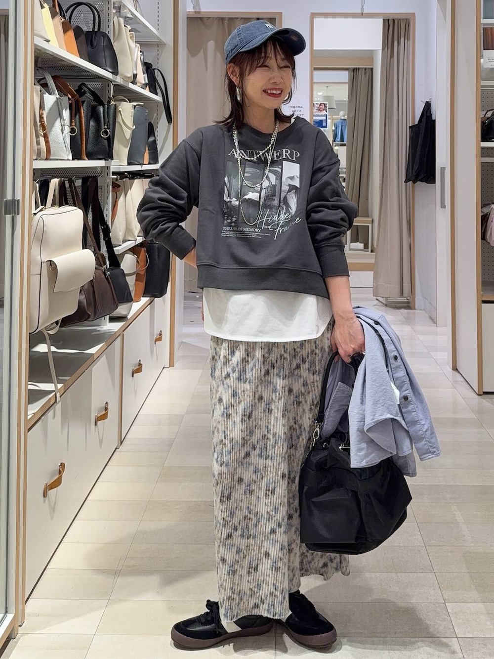 ブラック系のスニーカー、ブラック系のショルダーバッグ、ホワイト系のTシャツ/カットソーを着用したレディースの春コーディネートの2枚目の写真