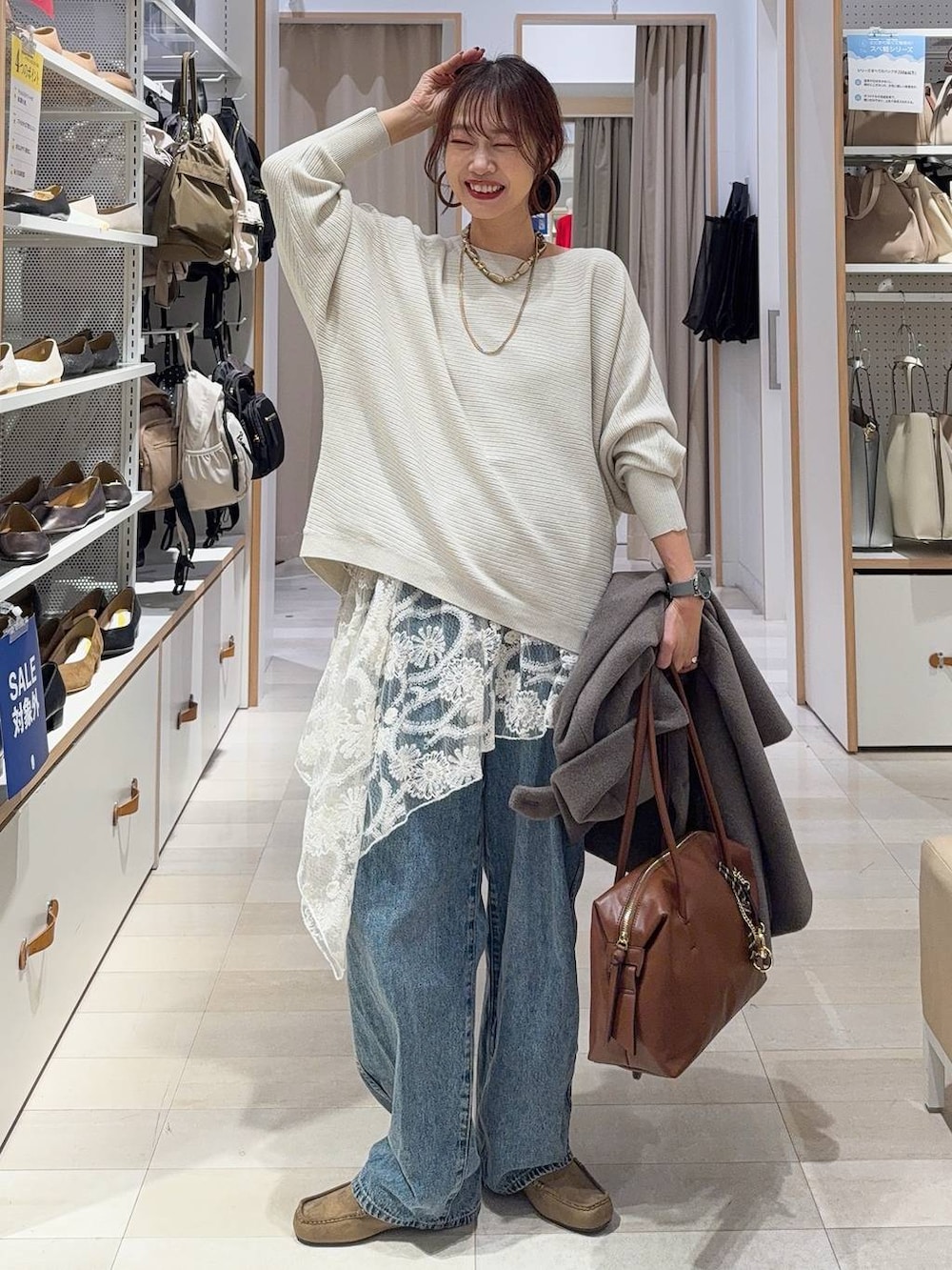 ブラウン系のボストンバッグ、ブルー系のデニムパンツ、ブラウン系のチェスターコートを着用したレディースの秋コーディネートの2枚目の写真