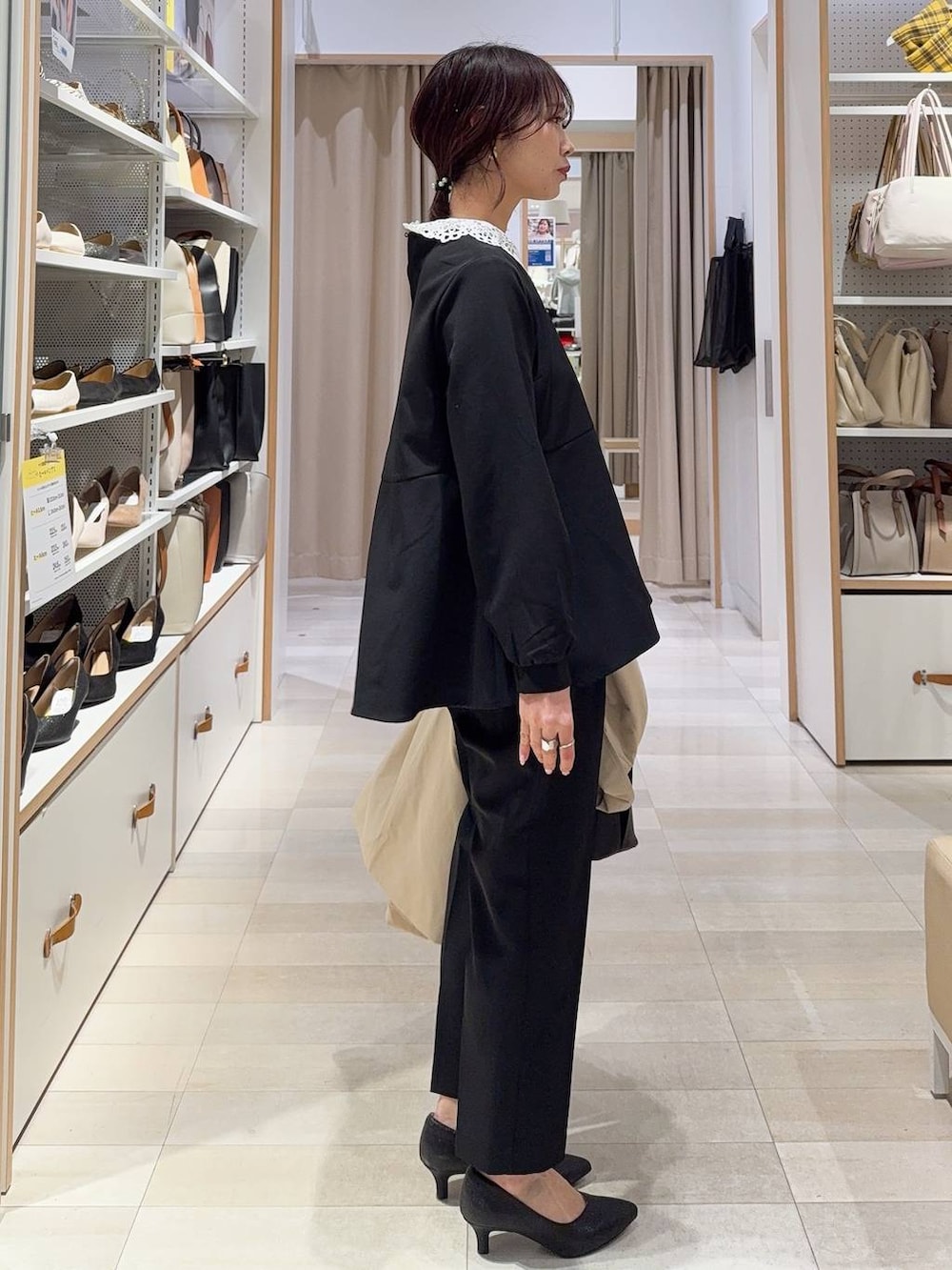 ホワイト系のショルダーバッグ、ブラック系のパンプス、ブラック系のセットアップを着用したレディースの冬コーディネートの6枚目の写真