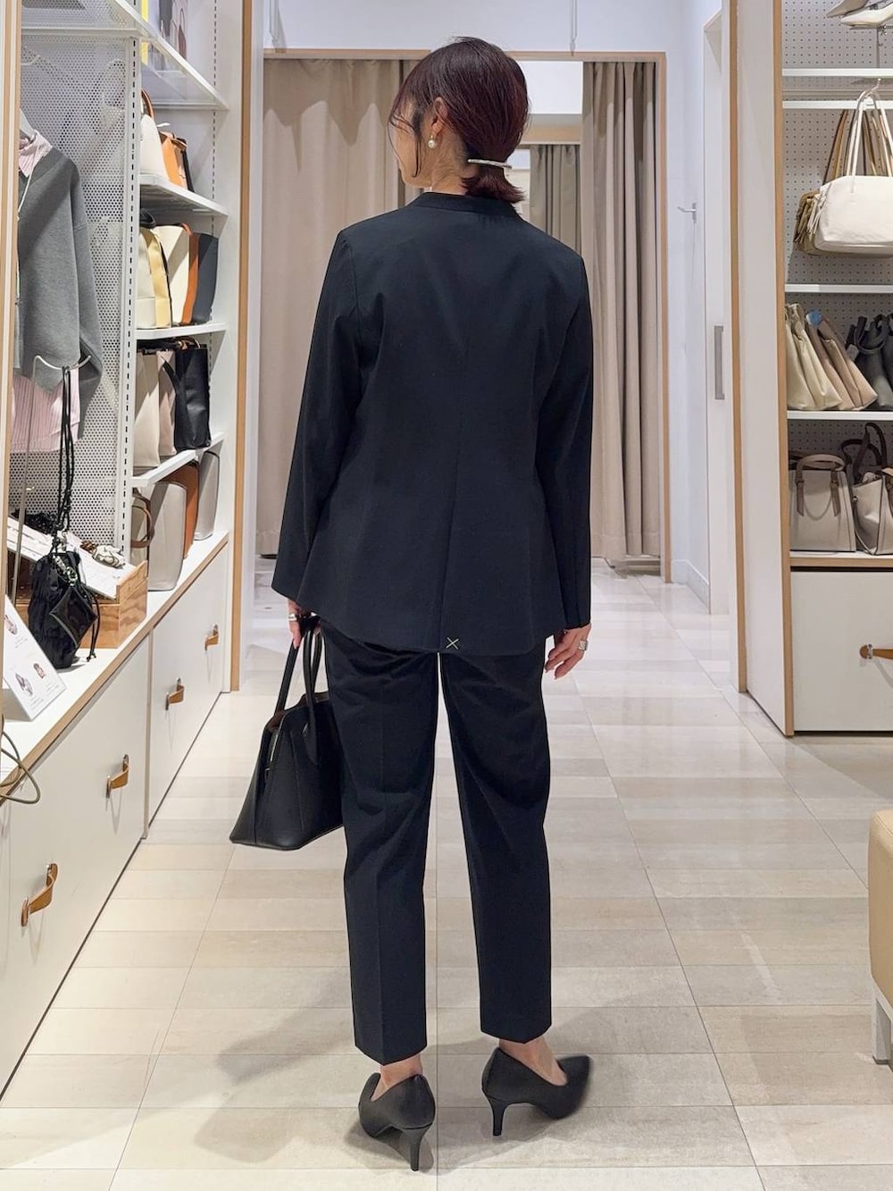 ブラック系のショルダーバッグ、ブルー系のスラックス、ホワイト系のシャツ/ブラウスを着用したレディースの冬コーディネートの5枚目の写真