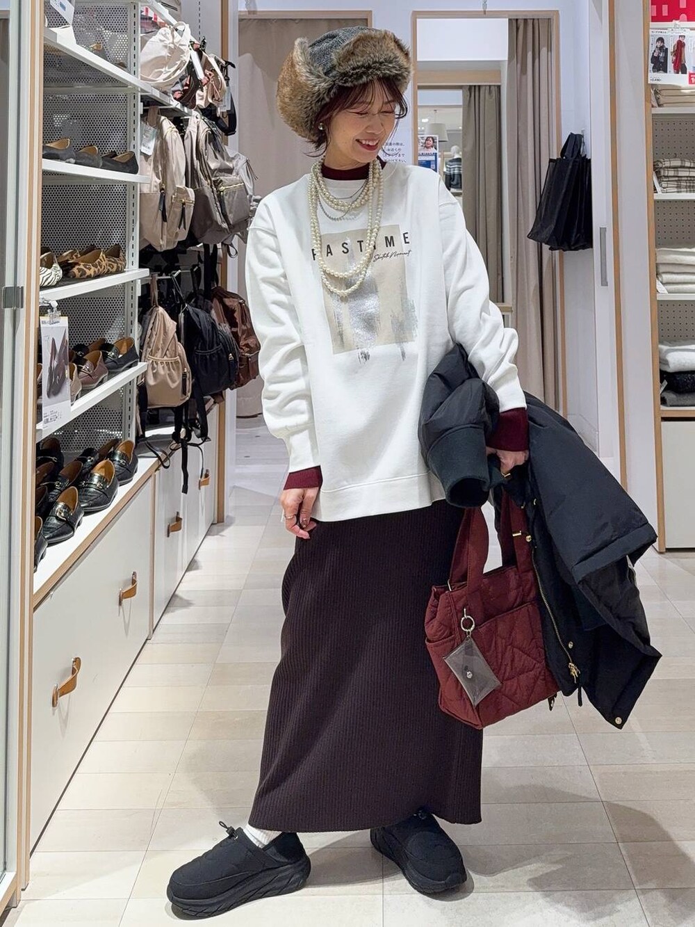 レッド系のトートバッグ、ブラック系のダウンジャケット/コート、レッド系のニット/セーターを着用したレディースの冬コーディネートの2枚目の写真