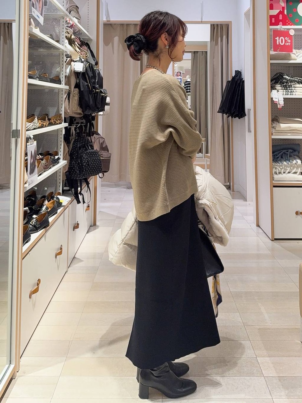 ベージュ系のダウンジャケット/コート、ブラック系のショルダーバッグ、ブラウン系のニット/セーターを着用したレディースの冬コーディネートの6枚目の写真