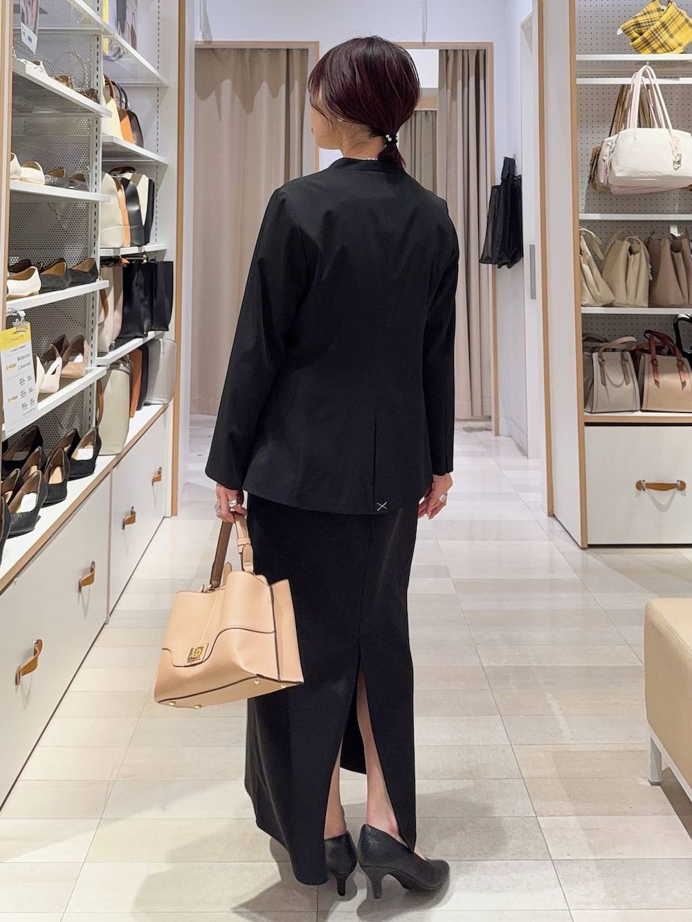 ブラック系のパンプス、ブラック系のノーカラージャケット、ベージュ系のショルダーバッグを着用したレディースの冬コーディネートの5枚目の写真