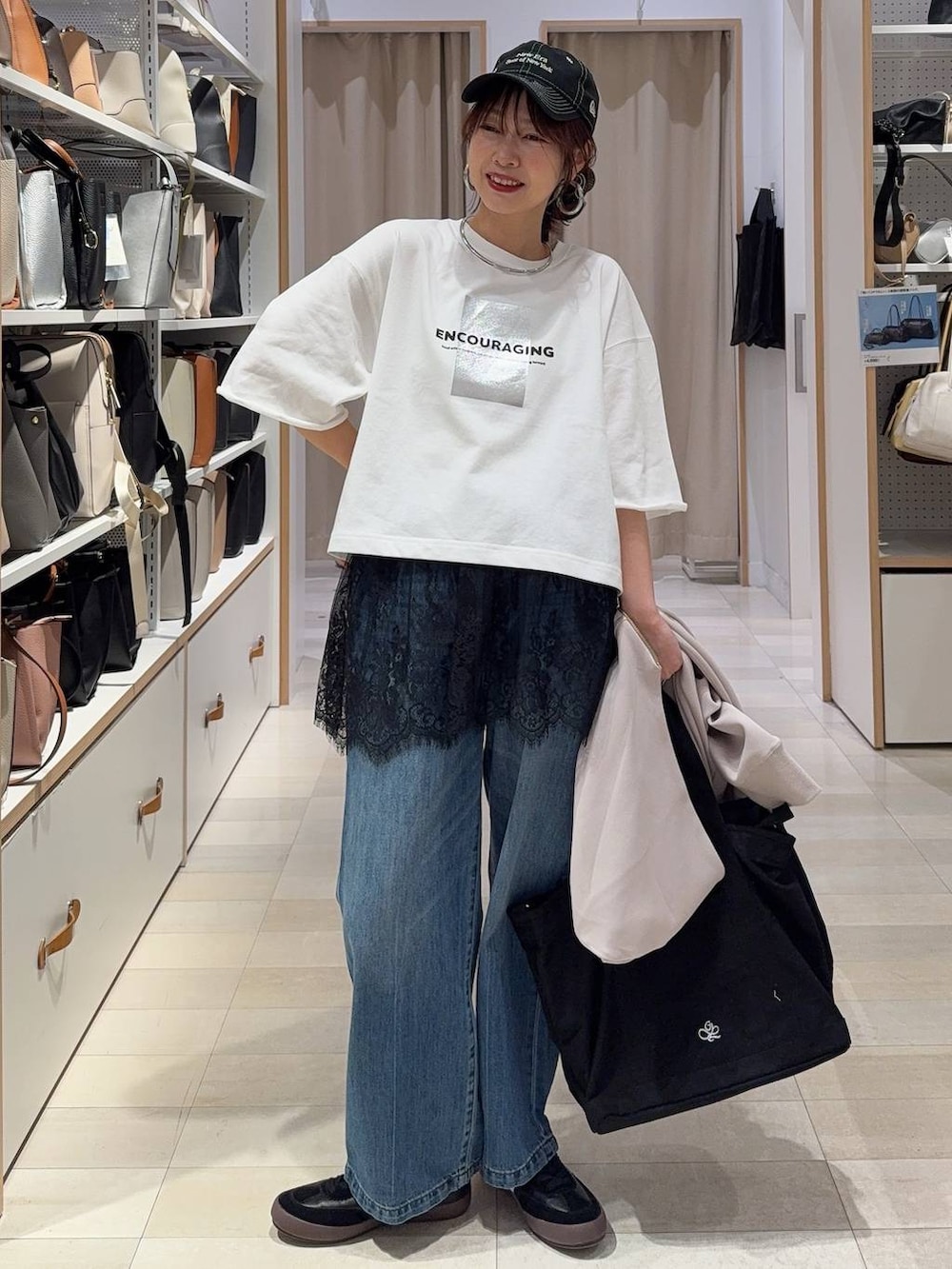 ブラック系のスニーカー、ブルー系のデニムパンツ、ベージュ系のパーカーを着用したレディースの春コーディネートの2枚目の写真