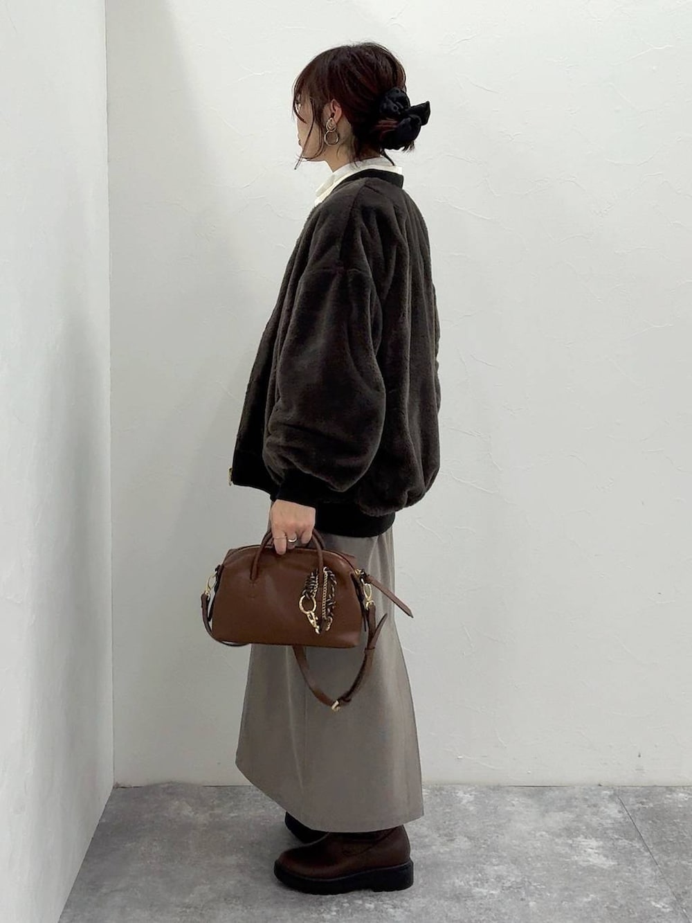 ブラック系のブルゾン、ブラウン系のスカート、ブラウン系のブーツを着用したレディースの冬コーディネートの5枚目の写真