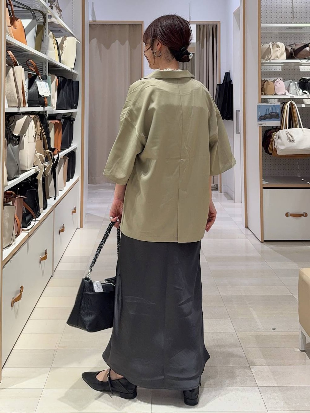 グレー系のスカート、ブラック系のパンプス、その他のネックレスを着用したレディースの春コーディネートの5枚目の写真