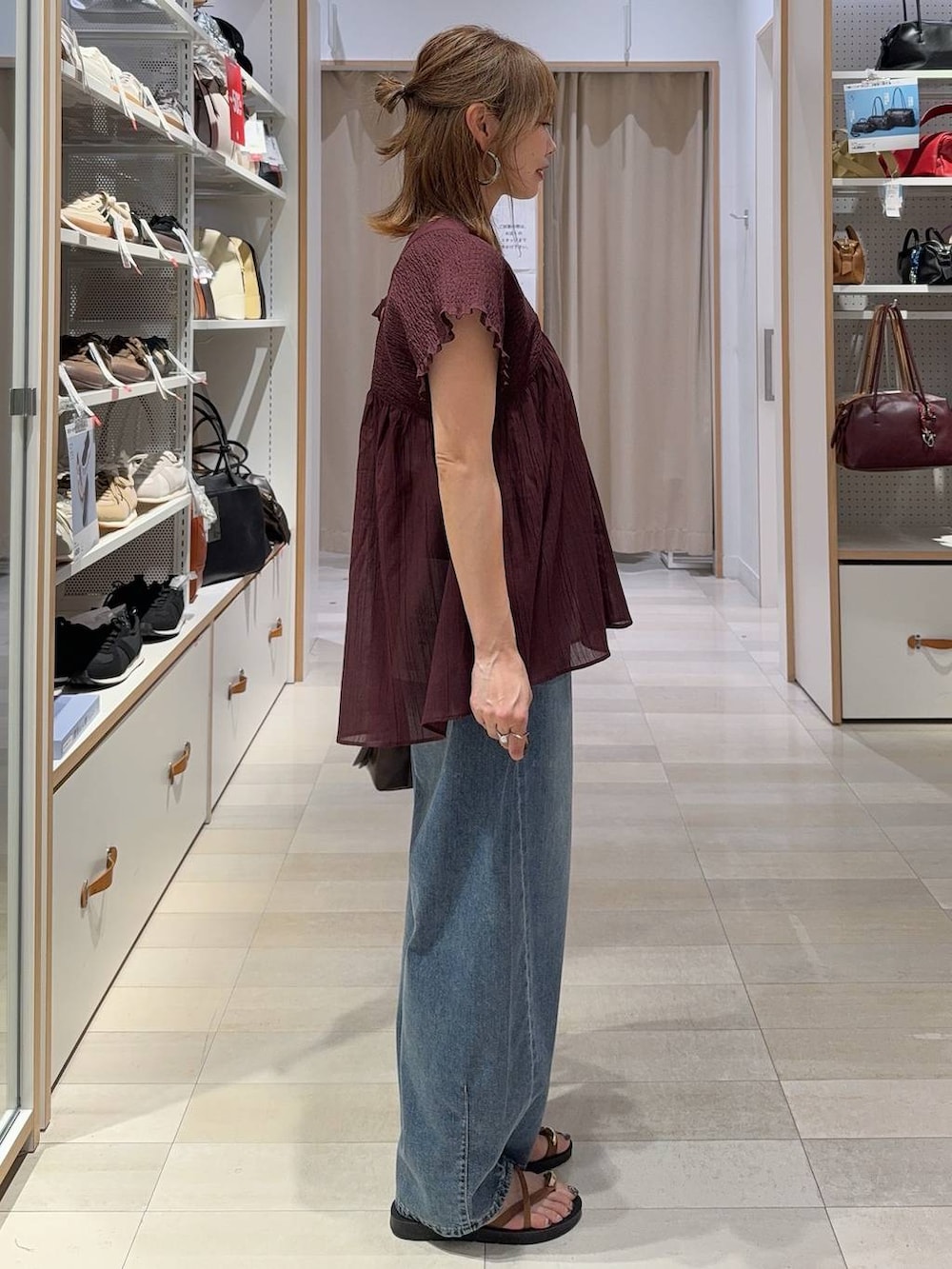 ブルー系のデニムパンツ、ブラウン系のボストンバッグ、レッド系のシャツ/ブラウスを着用したレディースの夏コーディネートの6枚目の写真