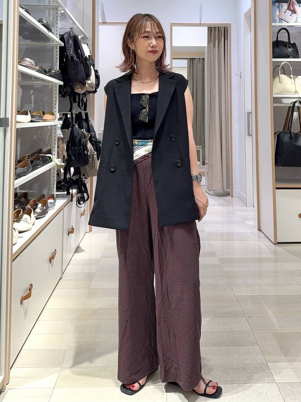 ブラック系のタンクトップ、ベージュ系のベスト、ブラウン系のその他パンツを着用したレディースの夏コーディネートの3枚目の写真