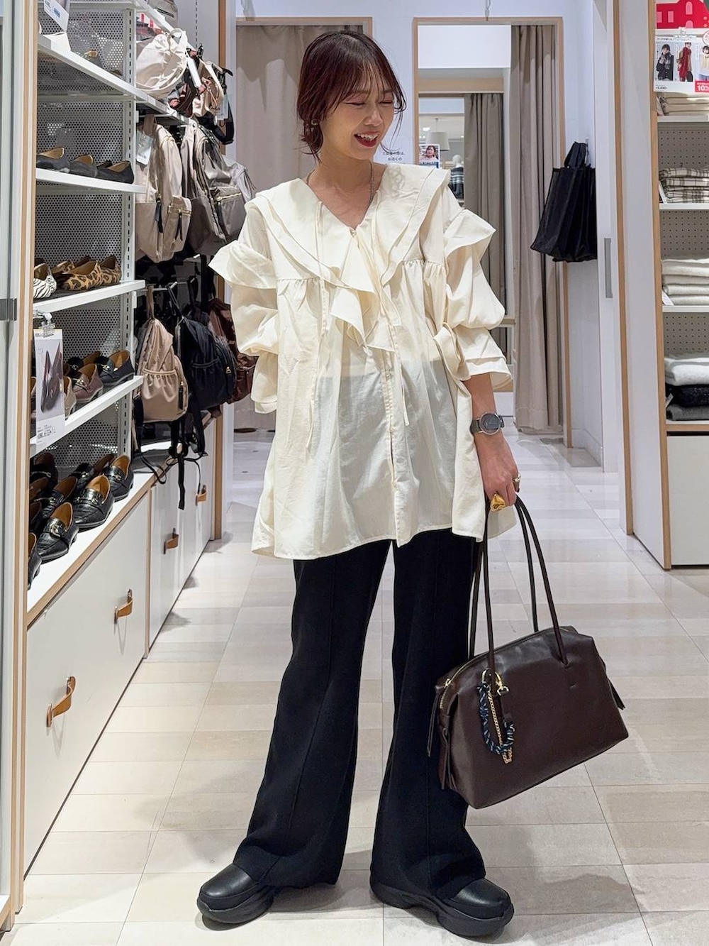 ブラウン系のボストンバッグ、ブラック系のブーツ、ブラウン系のカーディガン/ボレロを着用したレディースの冬コーディネートの2枚目の写真