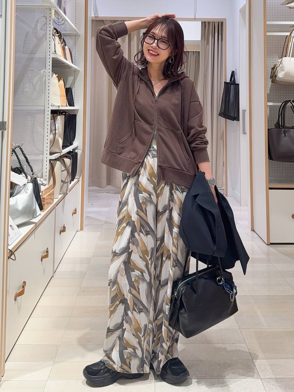 ブラック系のパンプス、ブラック系のハンドバッグ、ブルー系のデニムパンツを着用したレディースの春コーディネートの3枚目の写真