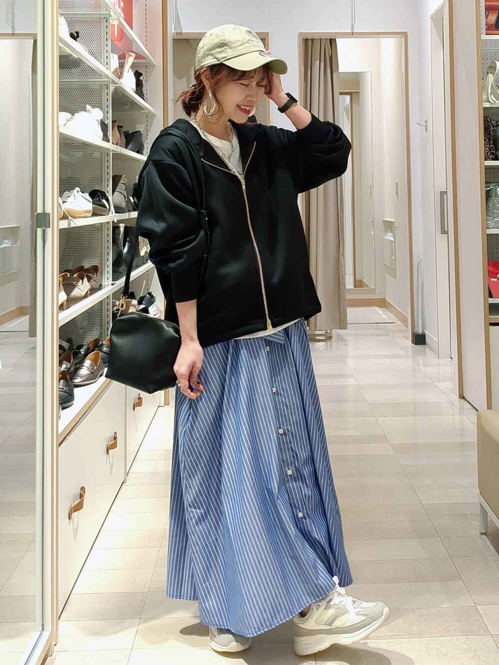 ベージュ系のデニムパンツ、ブラック系のパーカー、ブラック系のショルダーバッグを着用したレディースの春コーディネートの3枚目の写真