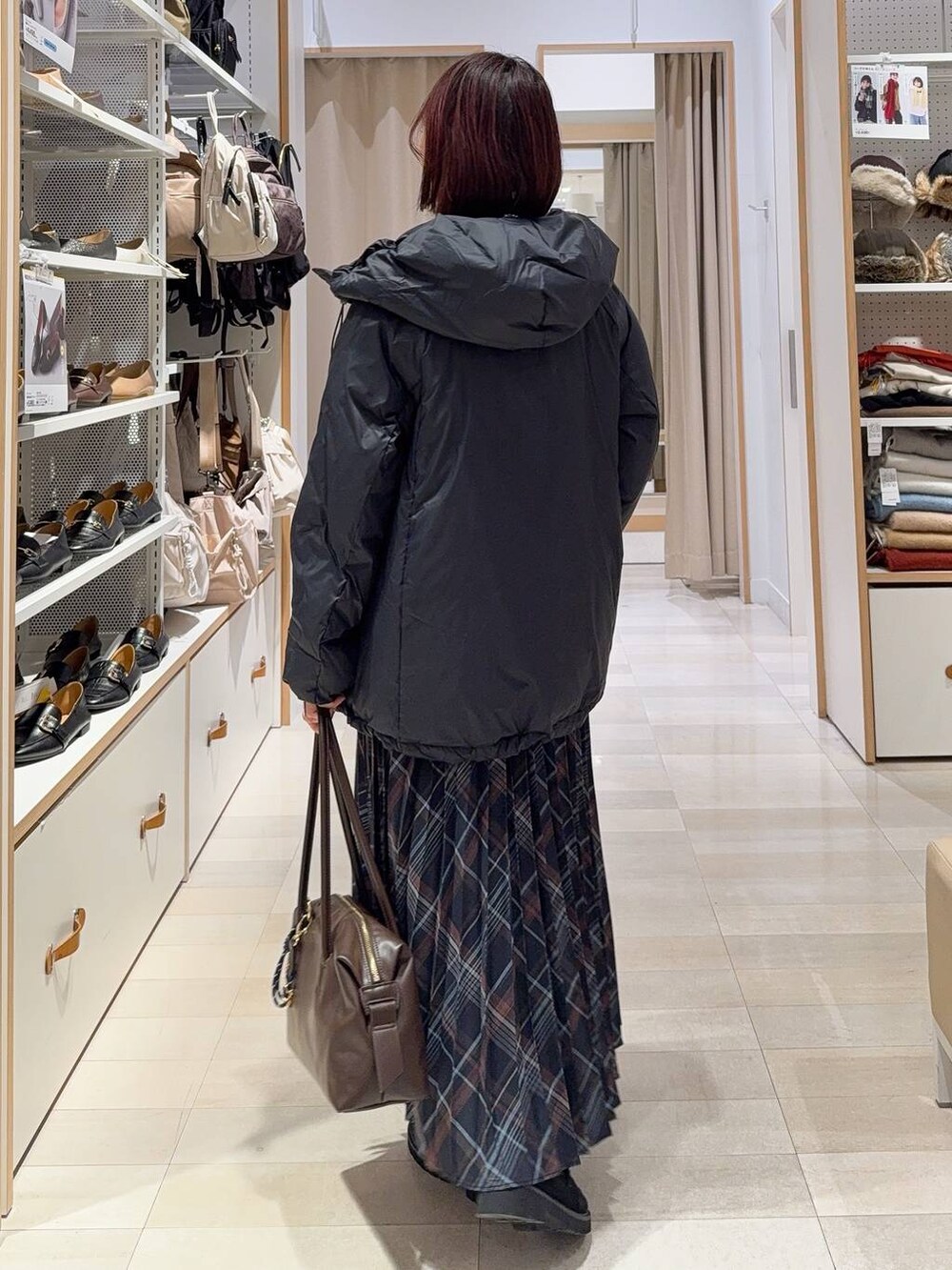 ブルー系のダウンジャケット/コート、ブラウン系のボストンバッグ、ブラック系のニット/セーターを着用したレディースの冬コーディネートの4枚目の写真