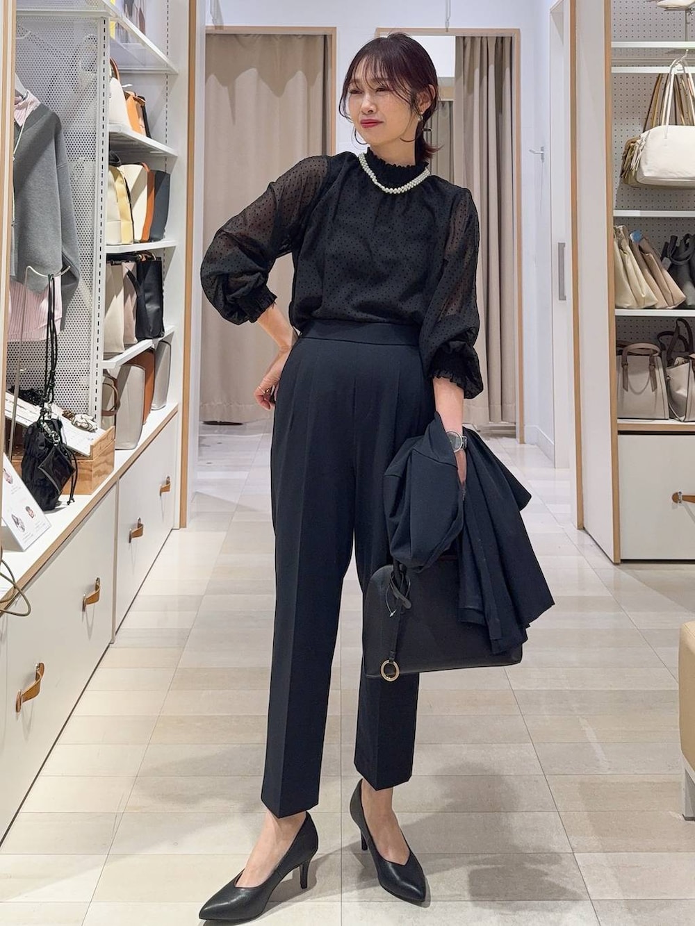 ブラック系のショルダーバッグ、ブルー系のスラックス、ブルー系のノーカラージャケットを着用したレディースの冬コーディネートの2枚目の写真