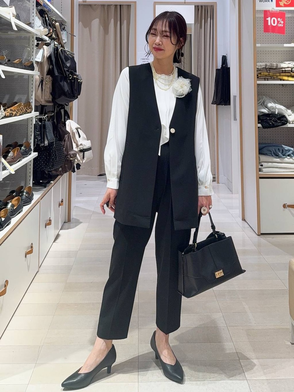 ブラック系のスラックス、ホワイト系のシャツ/ブラウス、ブラック系のその他アウターを着用したレディースの冬コーディネートの4枚目の写真