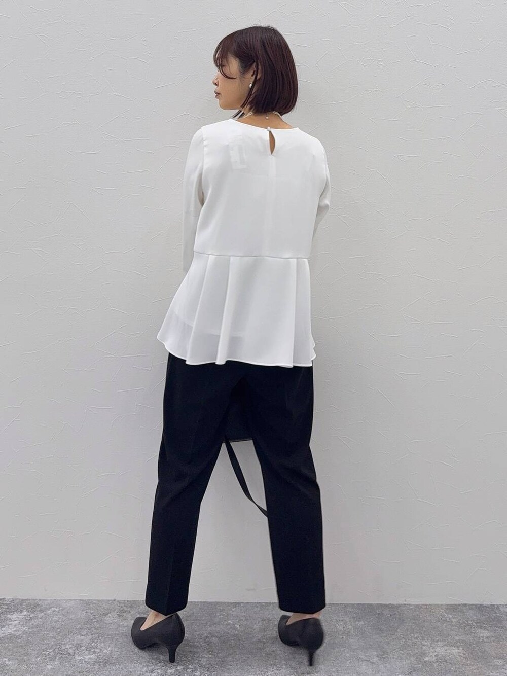 ブラック系のパンプス、ブラック系のセットアップ、その他のネックレスを着用したレディースの秋コーディネートの6枚目の写真