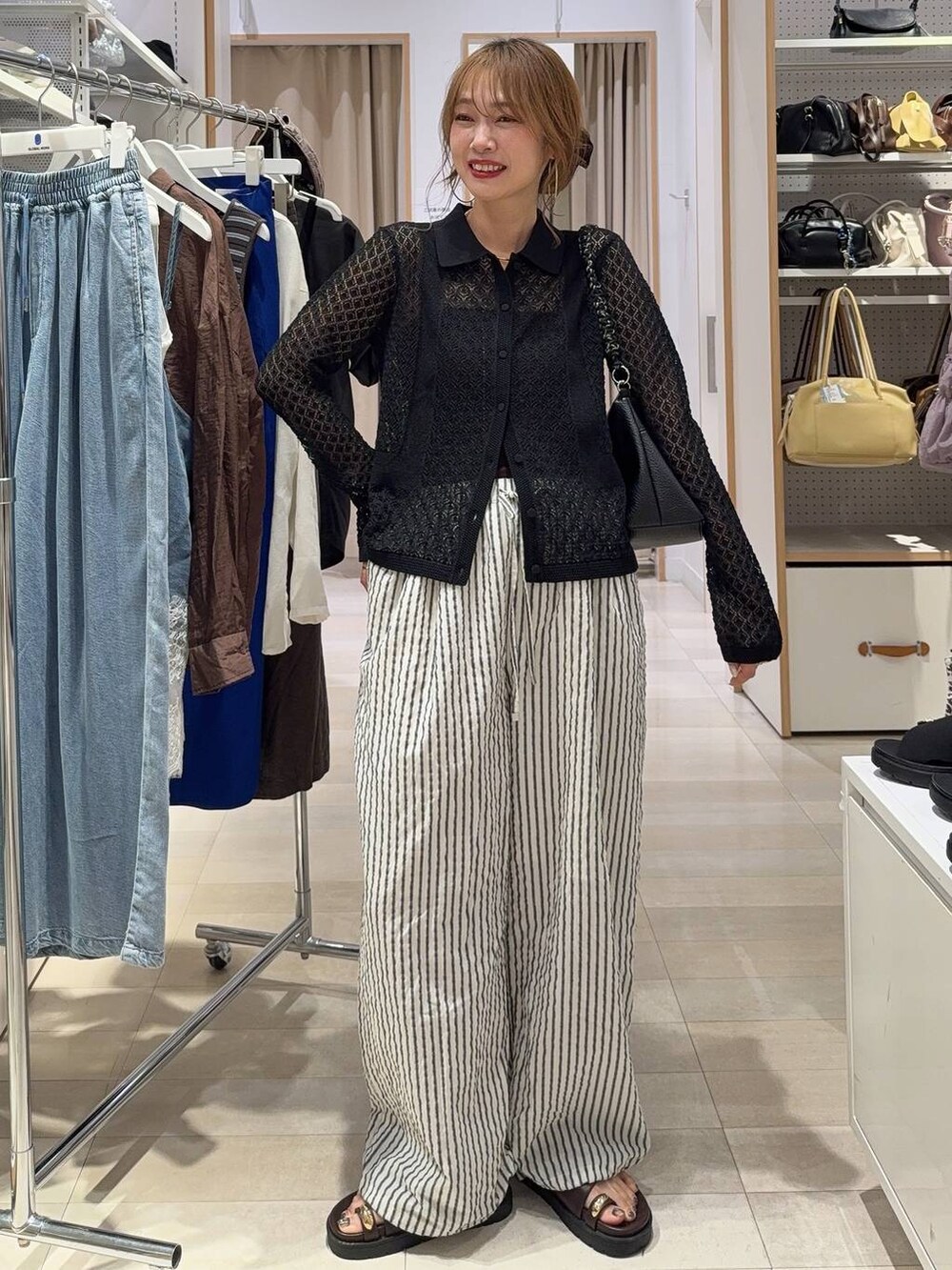 ブルー系のデニムパンツ、ブラック系のTシャツ/カットソー、ブラウン系のサンダルを着用したレディースの春コーディネートの2枚目の写真