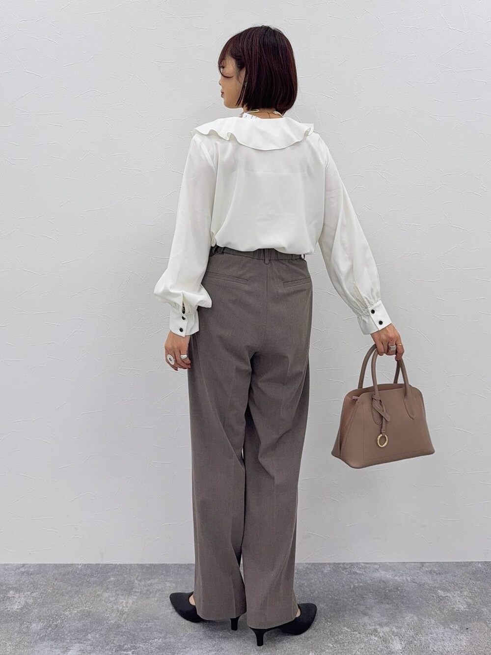 ベージュ系のショルダーバッグ、ブラック系のパンプス、ブラウン系のスラックスを着用したレディースの秋コーディネートの6枚目の写真