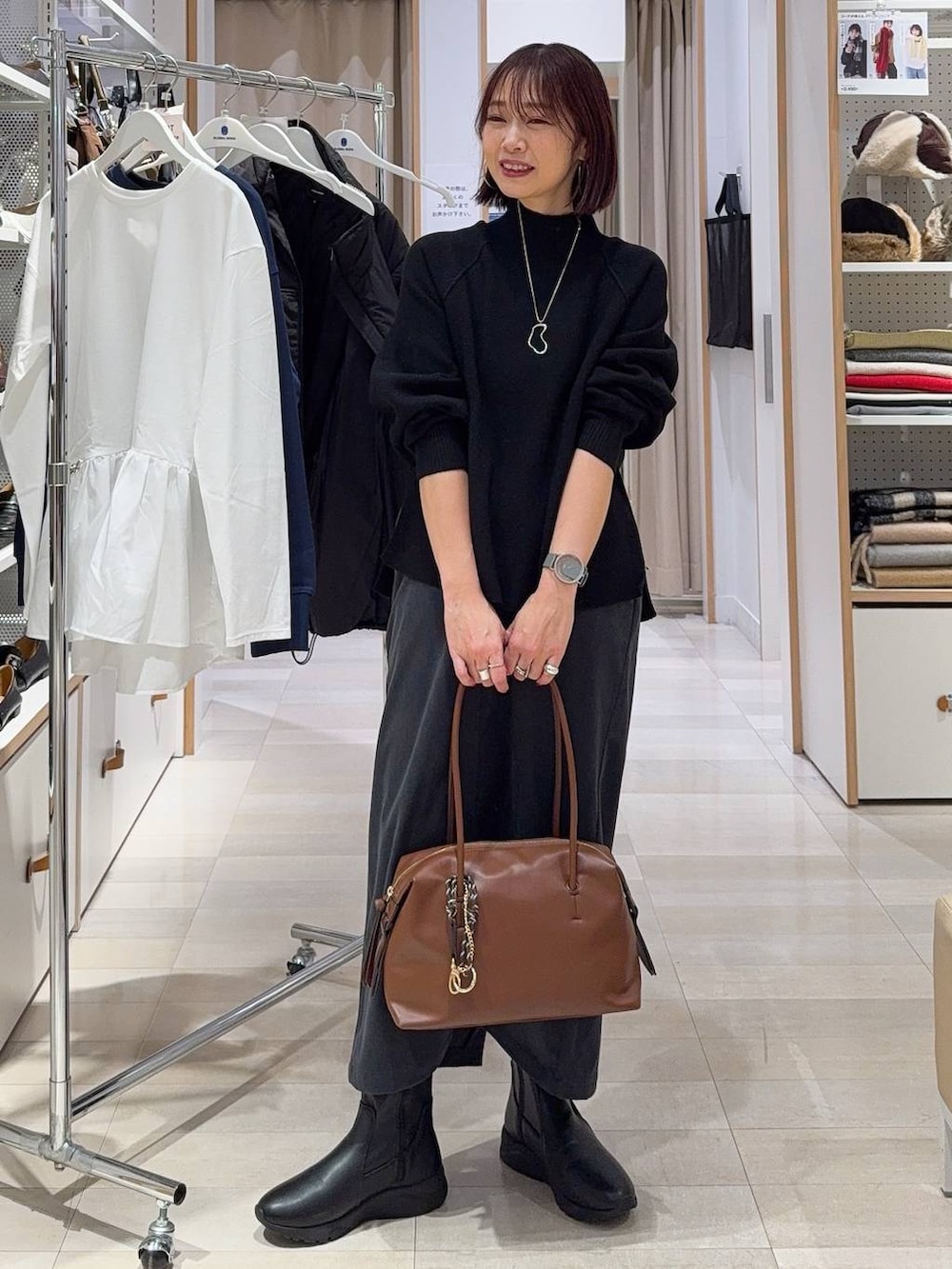 ブラウン系のボストンバッグ、ホワイト系のカーディガン/ボレロ、グレー系のスカートを着用したレディースの秋コーディネートの2枚目の写真