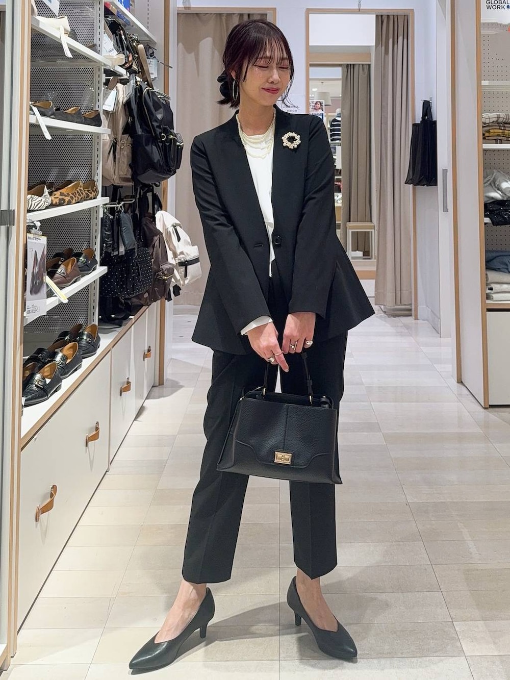 ブラック系のパンプス、ブラック系のノーカラージャケット、ベージュ系のショルダーバッグを着用したレディースの冬コーディネートの3枚目の写真