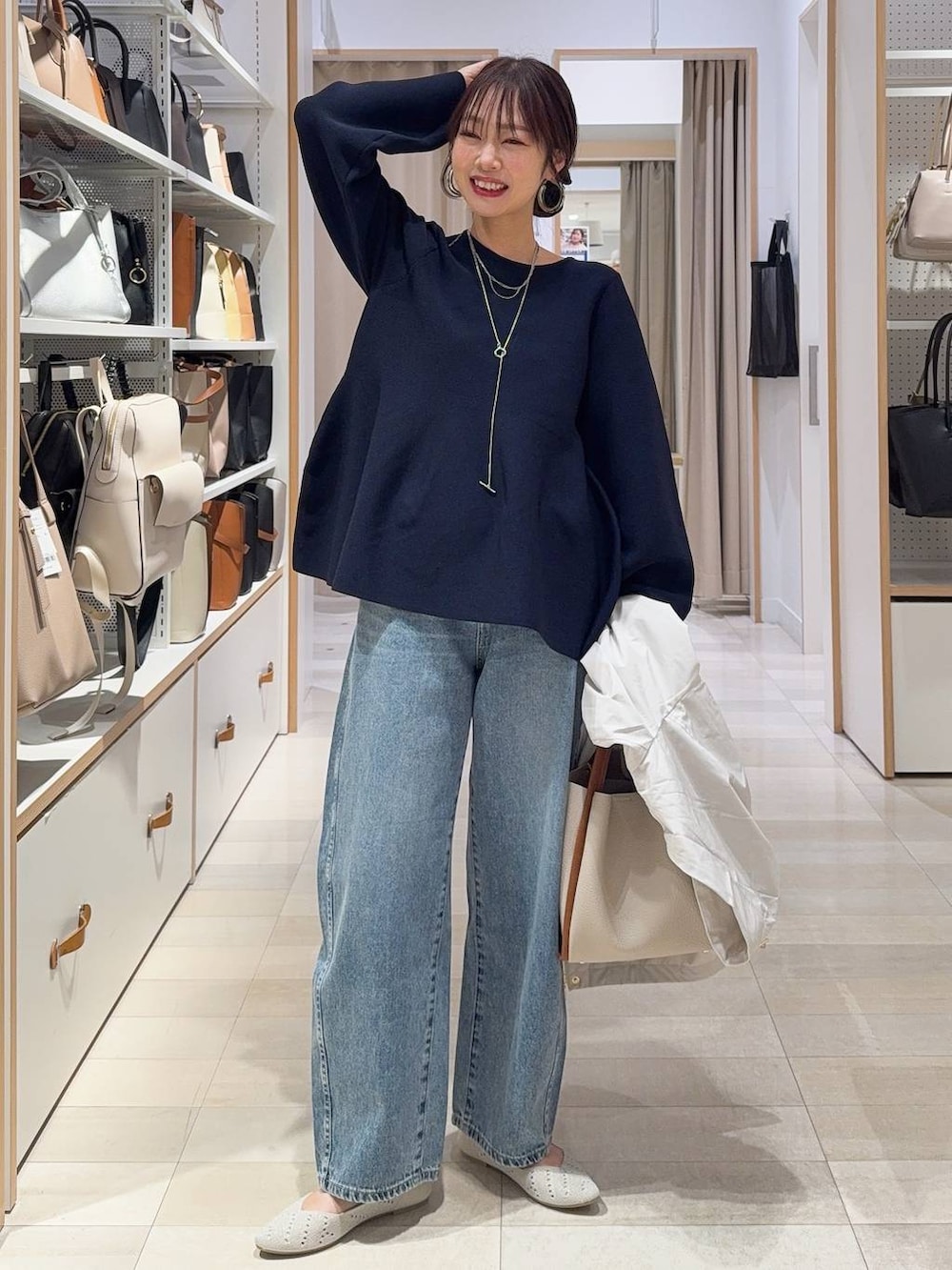 ベージュ系のトートバッグ、ベージュ系のマウンテンパーカー、ブルー系のデニムパンツを着用したレディースの春コーディネートの2枚目の写真