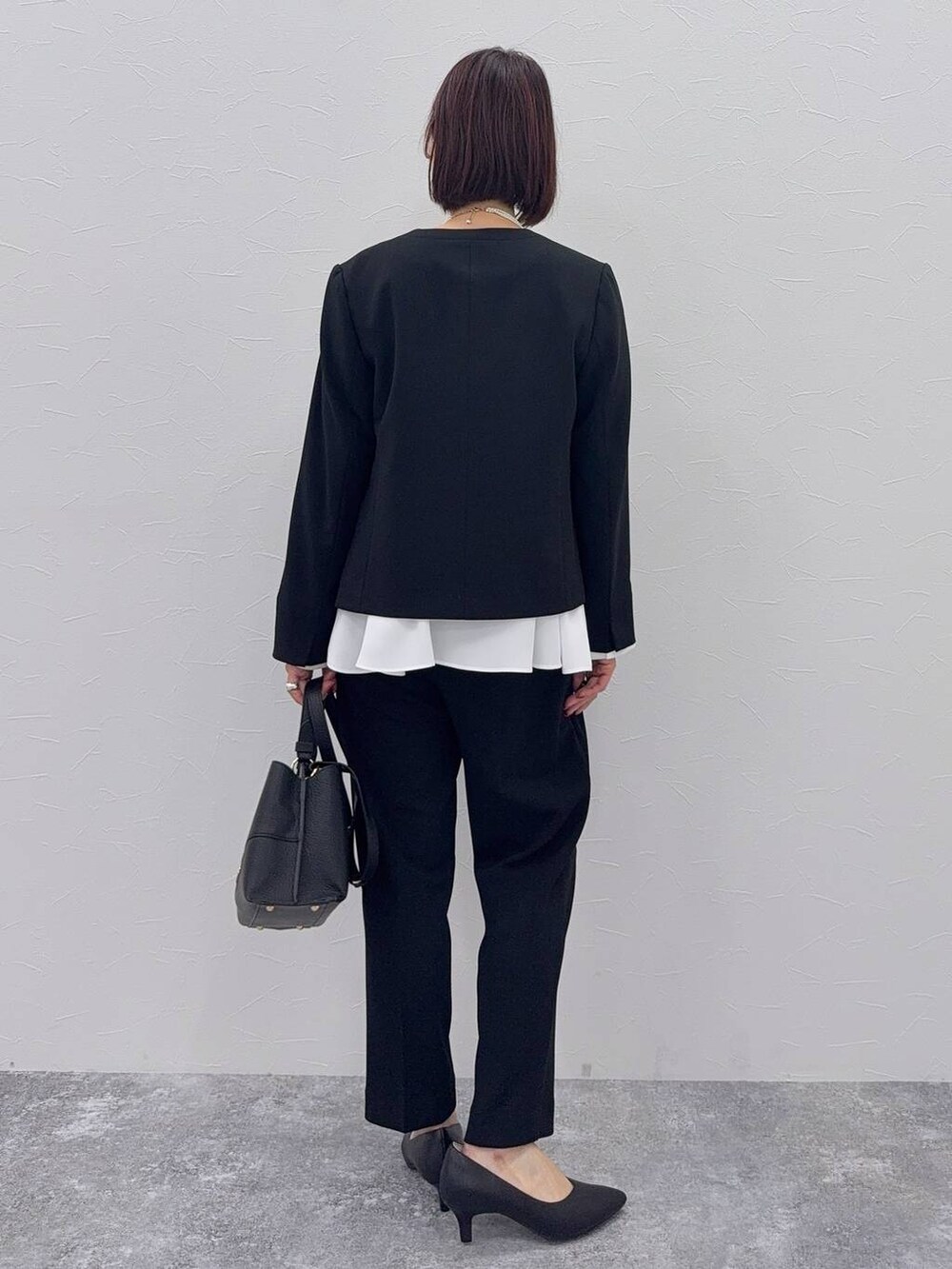 ブラック系のパンプス、ブラック系のセットアップ、その他のネックレスを着用したレディースの秋コーディネートの4枚目の写真