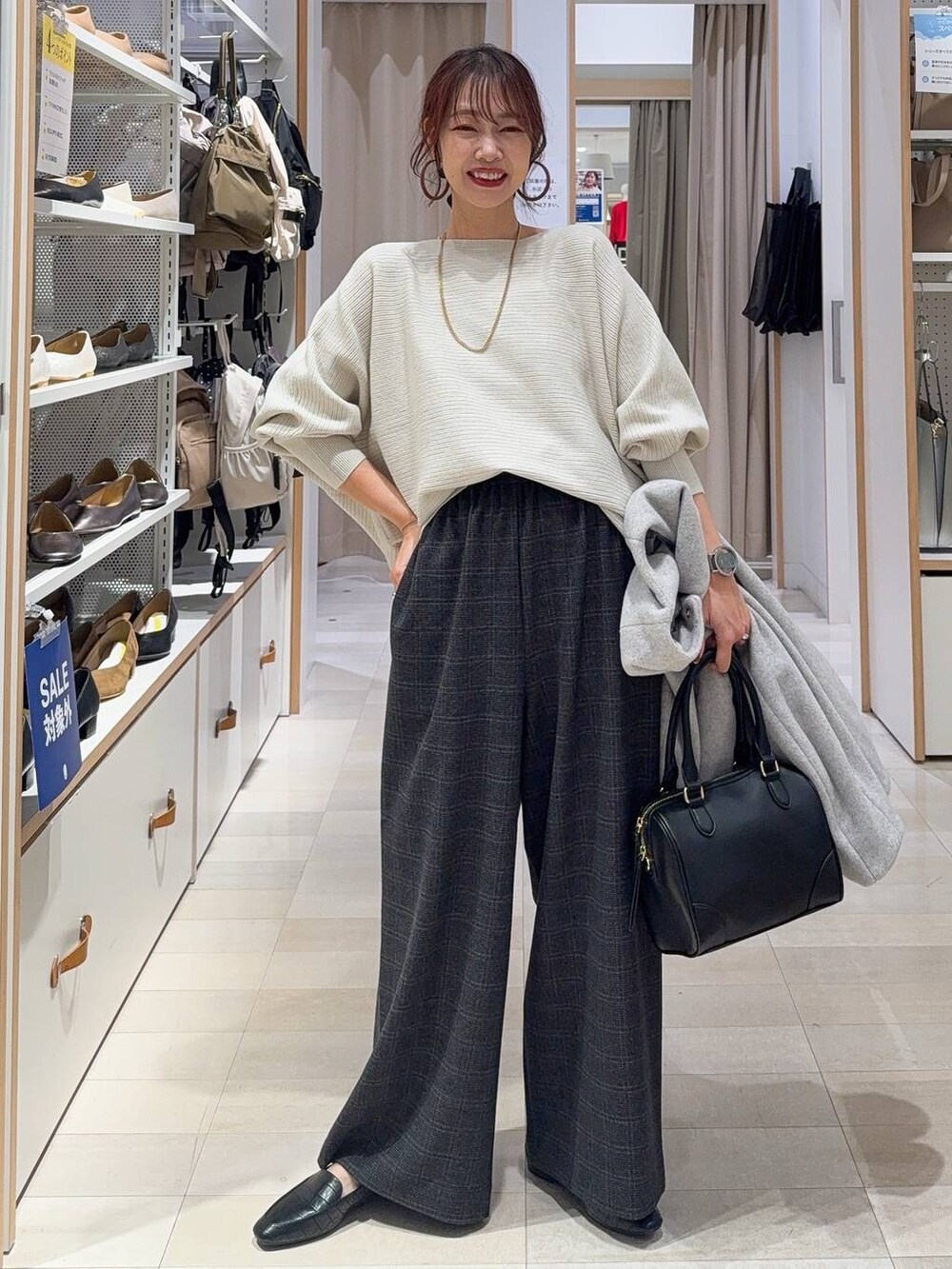 ブラウン系のボストンバッグ、ブルー系のデニムパンツ、ブラウン系のチェスターコートを着用したレディースの秋コーディネートの4枚目の写真