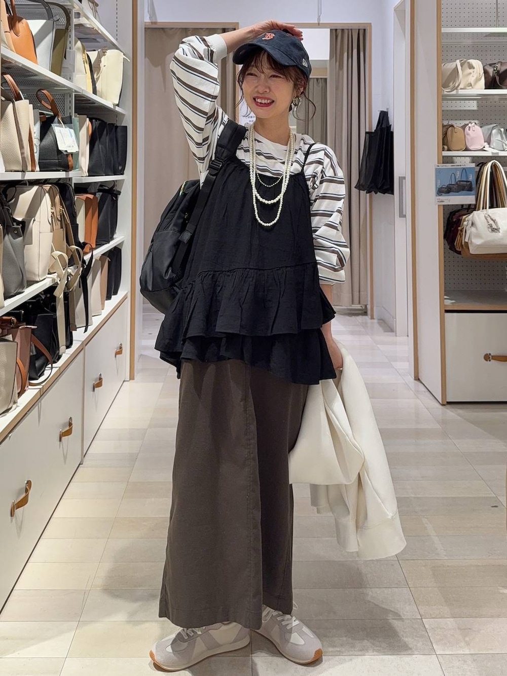 グレー系のスニーカー、ブラック系のバックパック/リュック、ホワイト系のパーカーを着用したレディースの春コーディネートの2枚目の写真