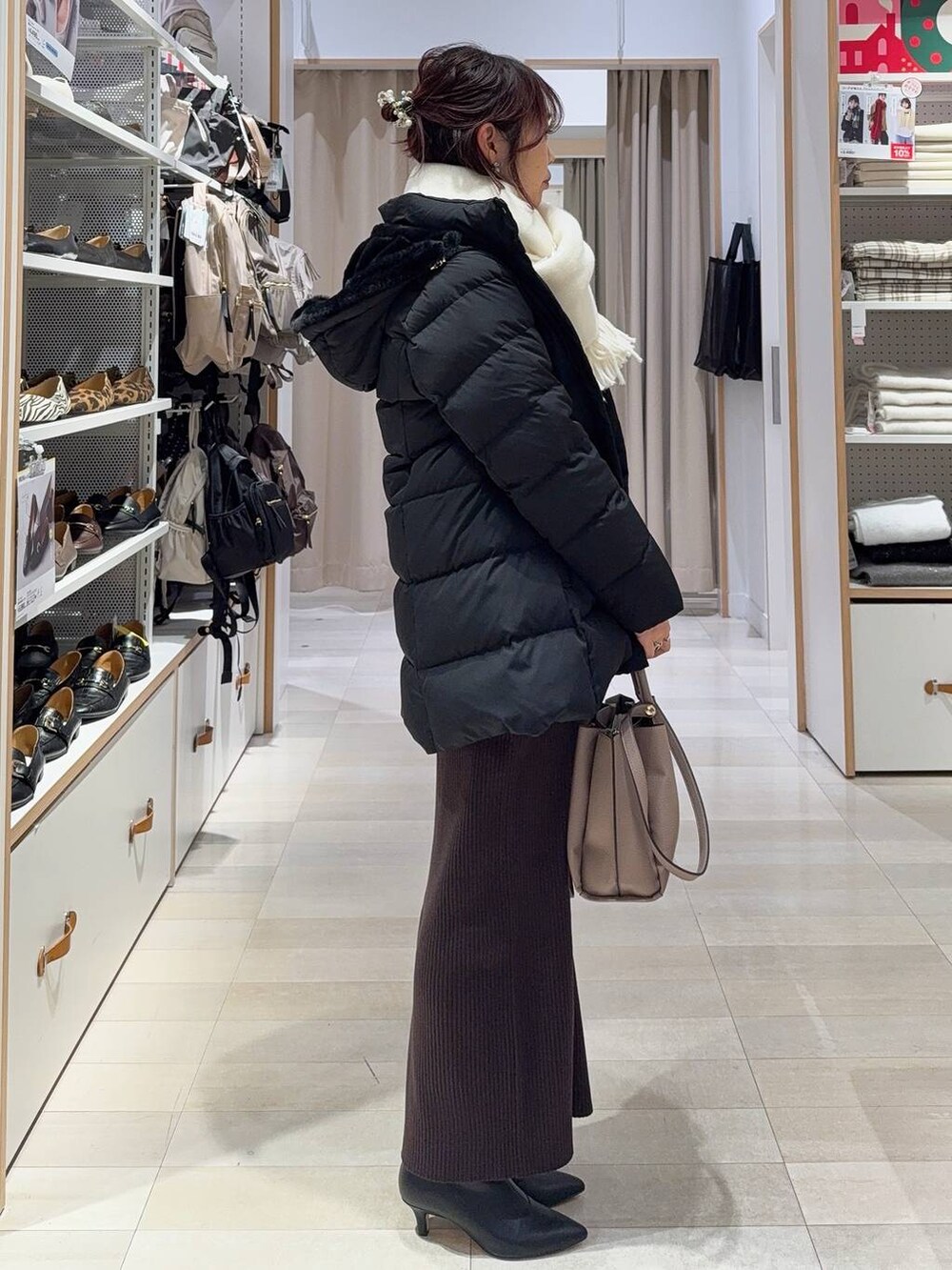 ブラック系のダウンジャケット/コート、ブラウン系のワンピース、ブラック系のブーツを着用したレディースの冬コーディネートの5枚目の写真