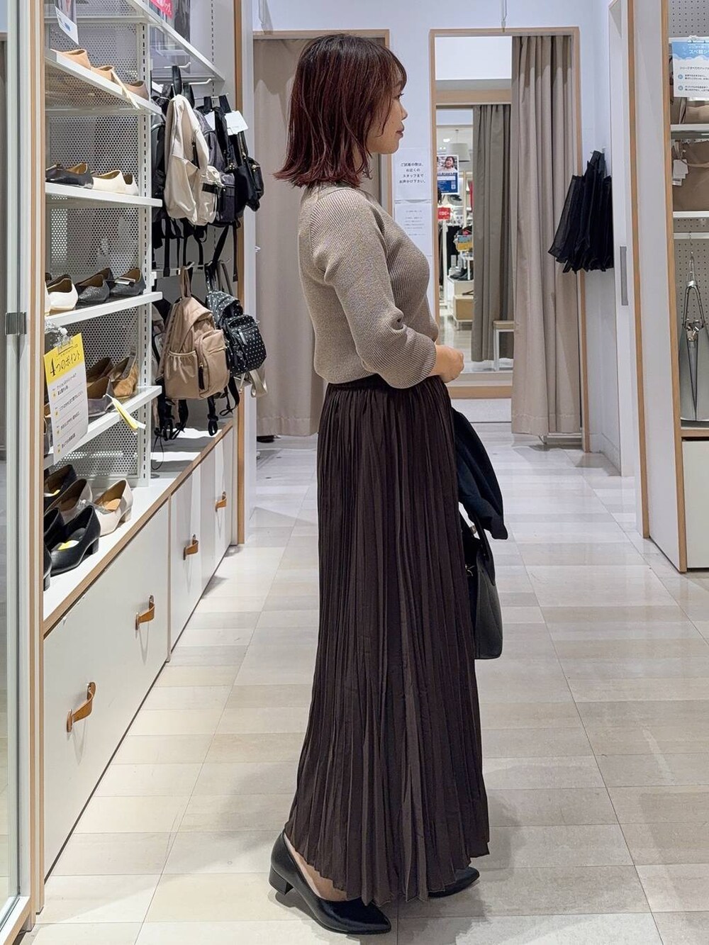 ブラック系のショルダーバッグ、ベージュ系のニット/セーター、ブラウン系のブーツを着用したレディースの秋コーディネートの6枚目の写真