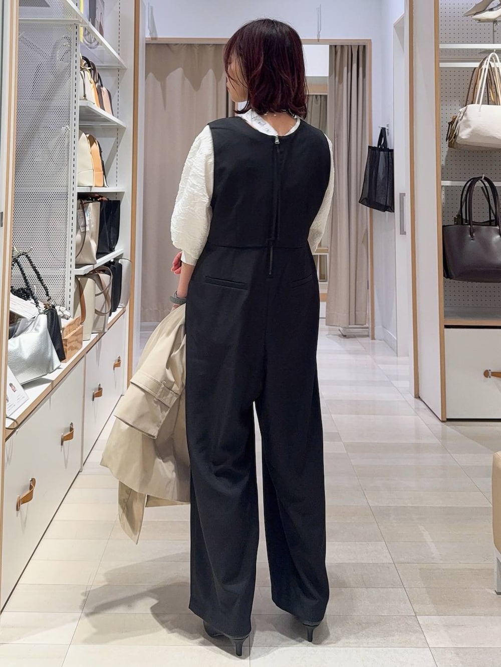 ブラック系のショルダーバッグ、ブラック系のパンプス、ベージュ系のステンカラーコートを着用したレディースの冬コーディネートの6枚目の写真