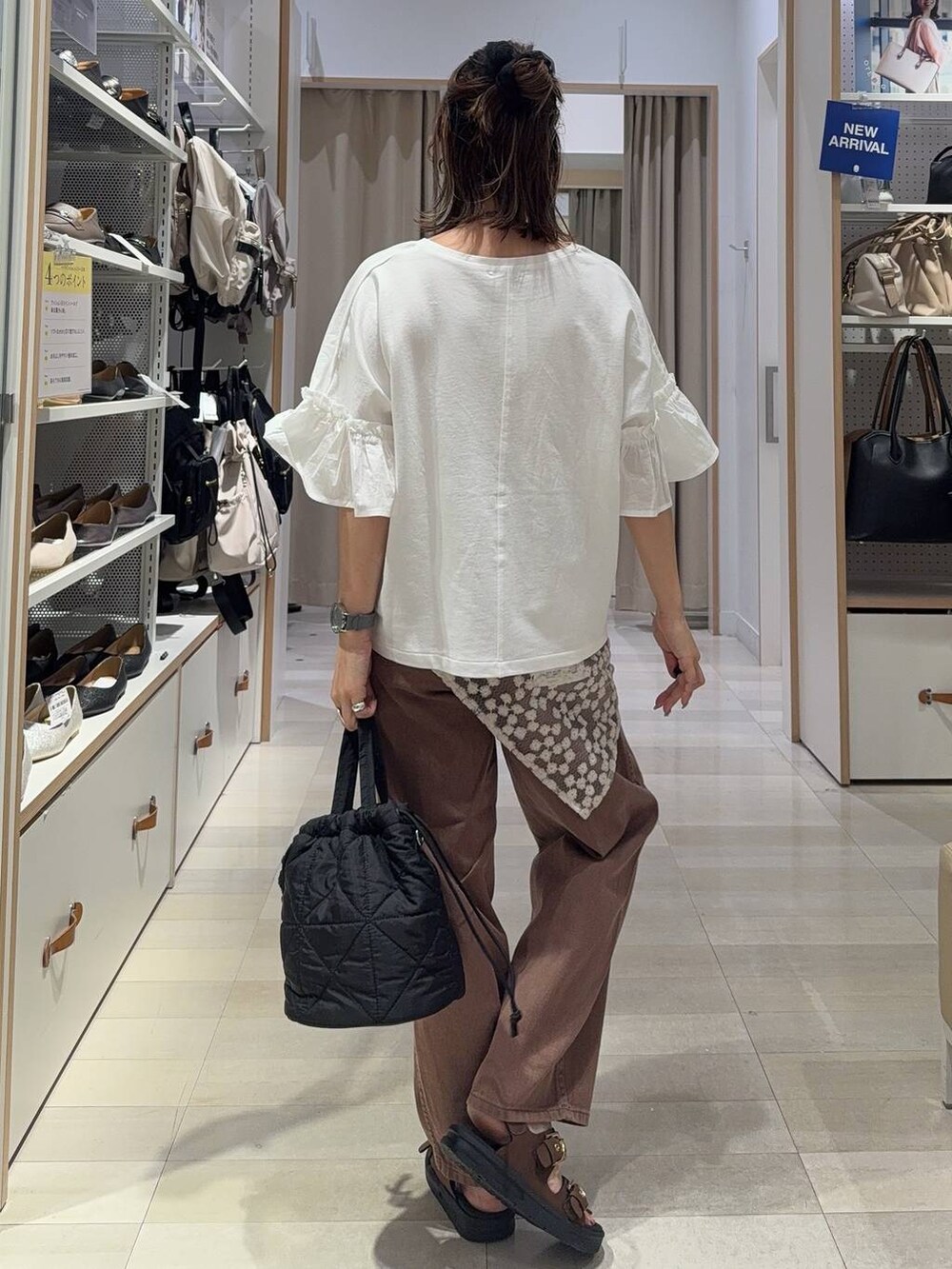 ブラウン系のサンダル、ブラウン系のデニムパンツ、ブラック系のハンドバッグを着用したレディースの夏コーディネートの5枚目の写真