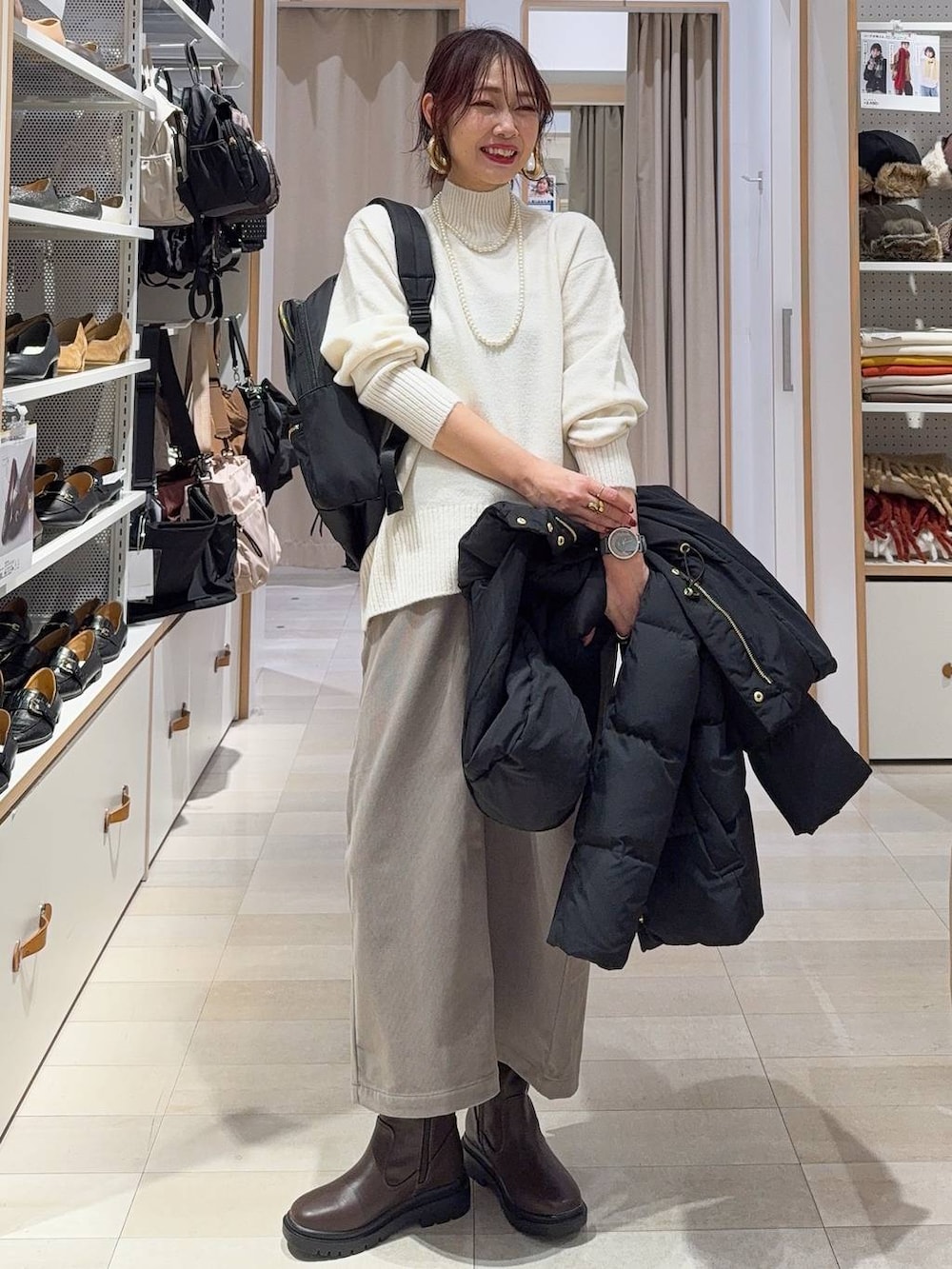 ブラック系のブルゾン、ブラウン系のスカート、ブラウン系のブーツを着用したレディースの冬コーディネートの4枚目の写真