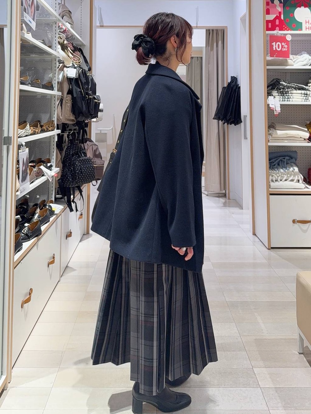 ブラック系のショルダーバッグ、ブルー系のチェスターコート、グレー系のスカートを着用したレディースの冬コーディネートの8枚目の写真