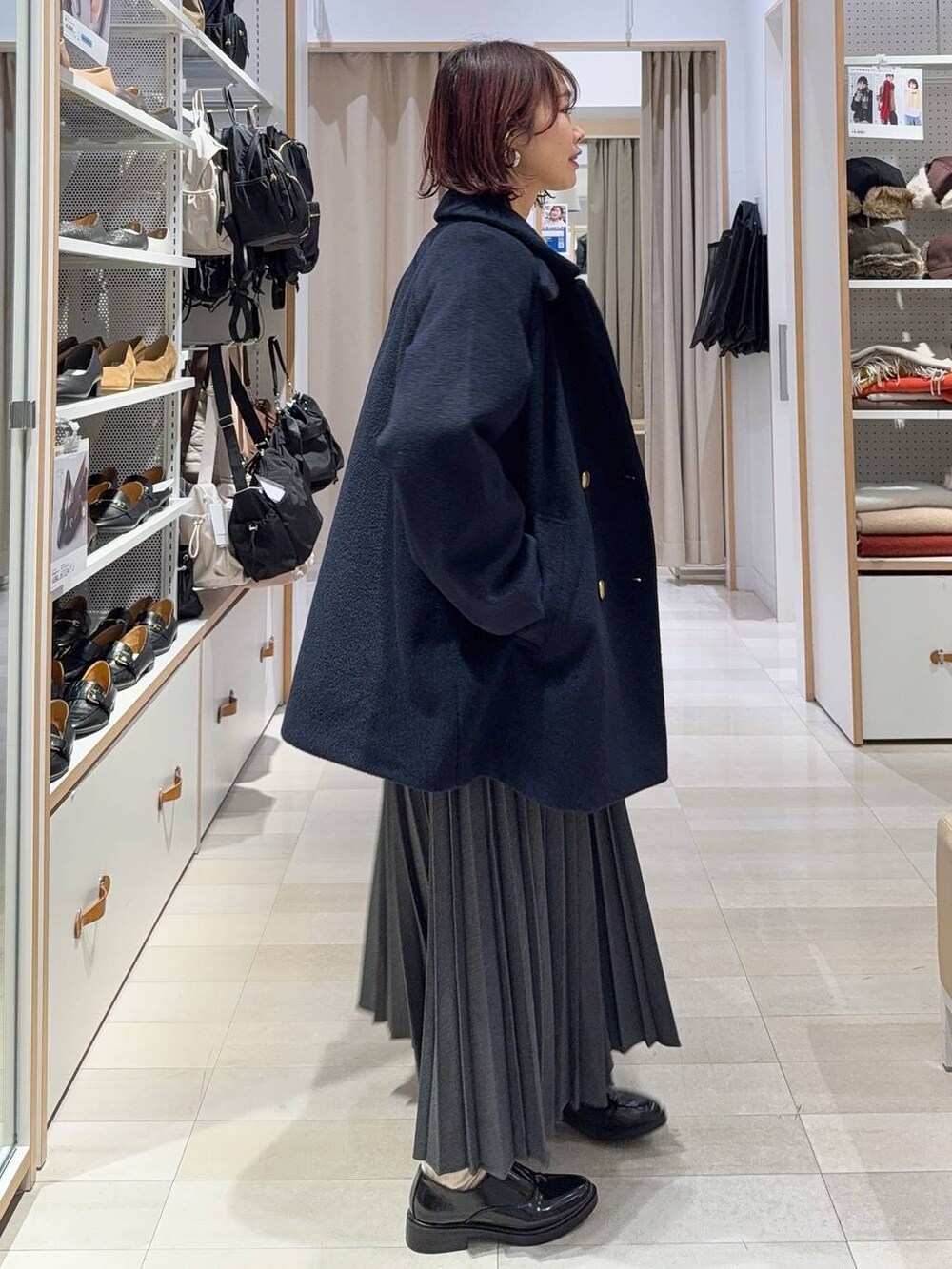 ブラック系のボストンバッグ、ブルー系のチェスターコート、イエロー系のシャツ/ブラウスを着用したレディースの冬コーディネートの4枚目の写真