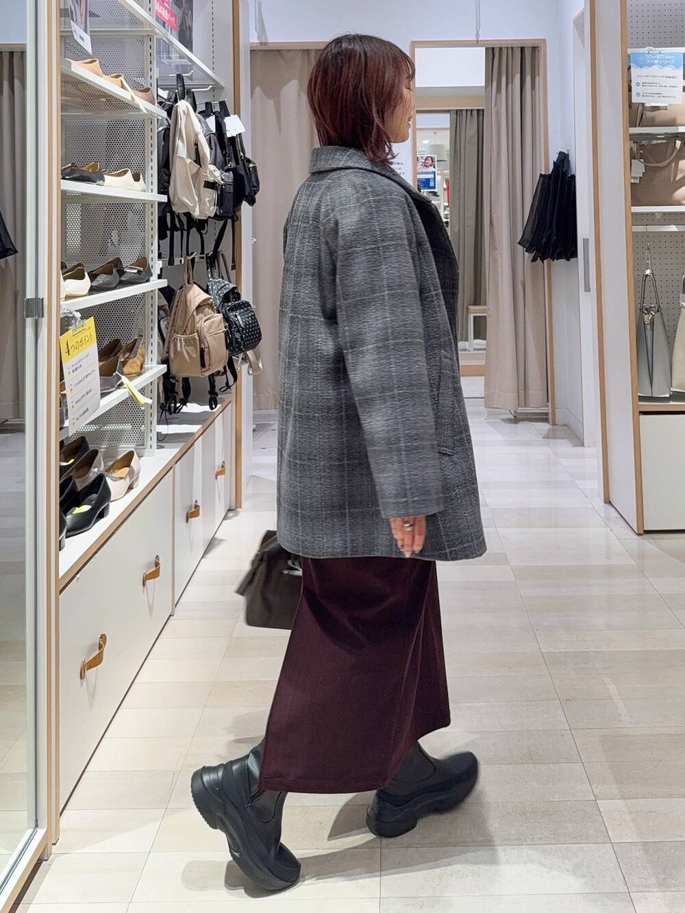 ブラウン系のボストンバッグ、グレー系のチェスターコート、レッド系のスカートを着用したレディースの秋コーディネートの4枚目の写真